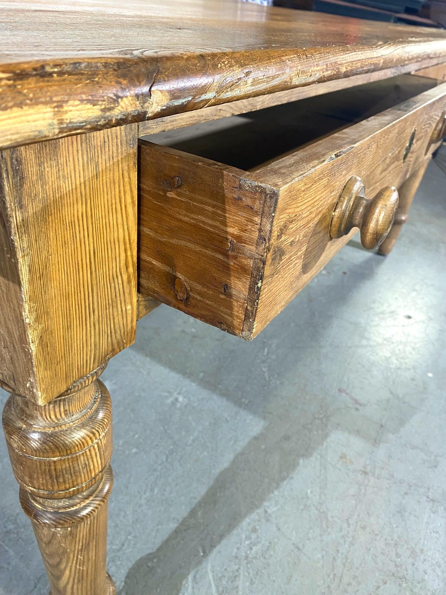 Table de cuisine en pin massif. Pieds tournés et tiroirs de chaque côté.