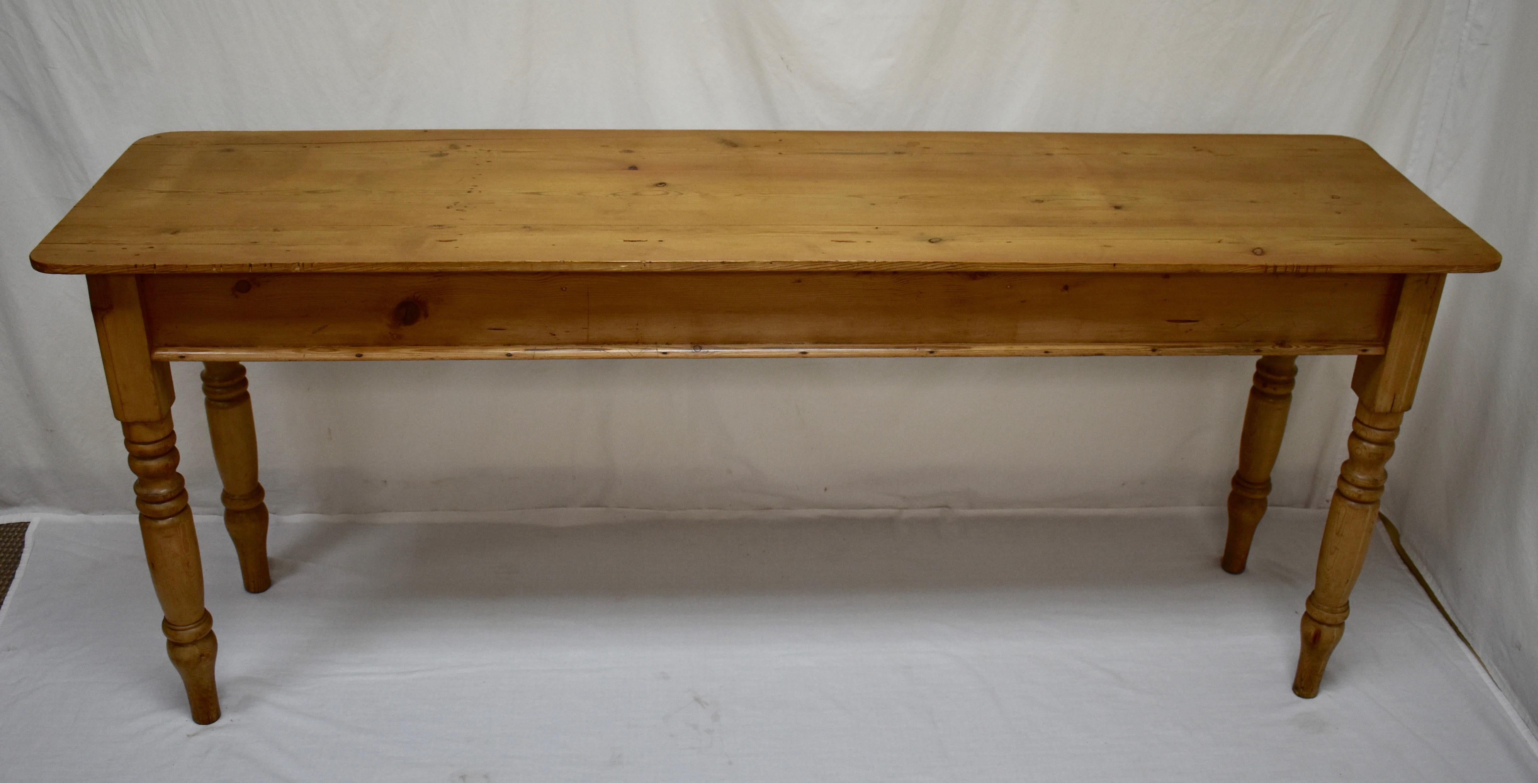 This is a well-proportioned late 19th century English pine side table. The thin three board top is reinforced by two sturdy cross members on the underside. It is somewhat stained with some small repairs. The turned legs are nicely rounded at the top