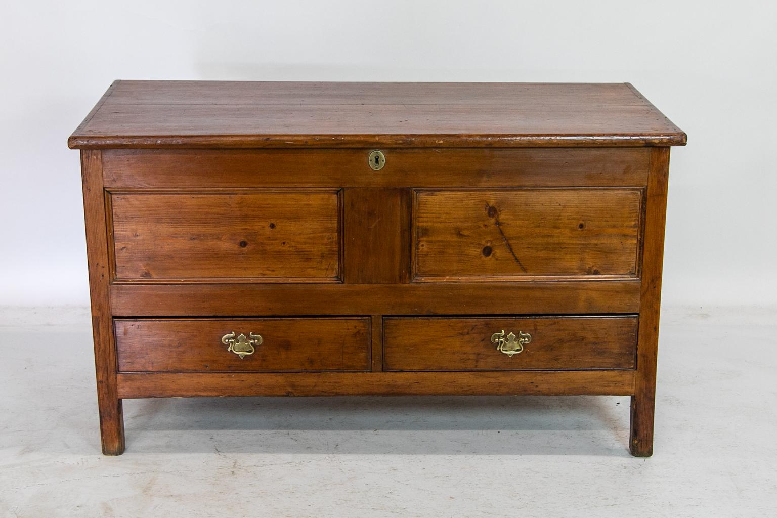 This pine blanket chest has a bullnose top molding and recessed molded panels on the front and sides. The two drawers have incised cockbeaded edges. The interior retains its two large 