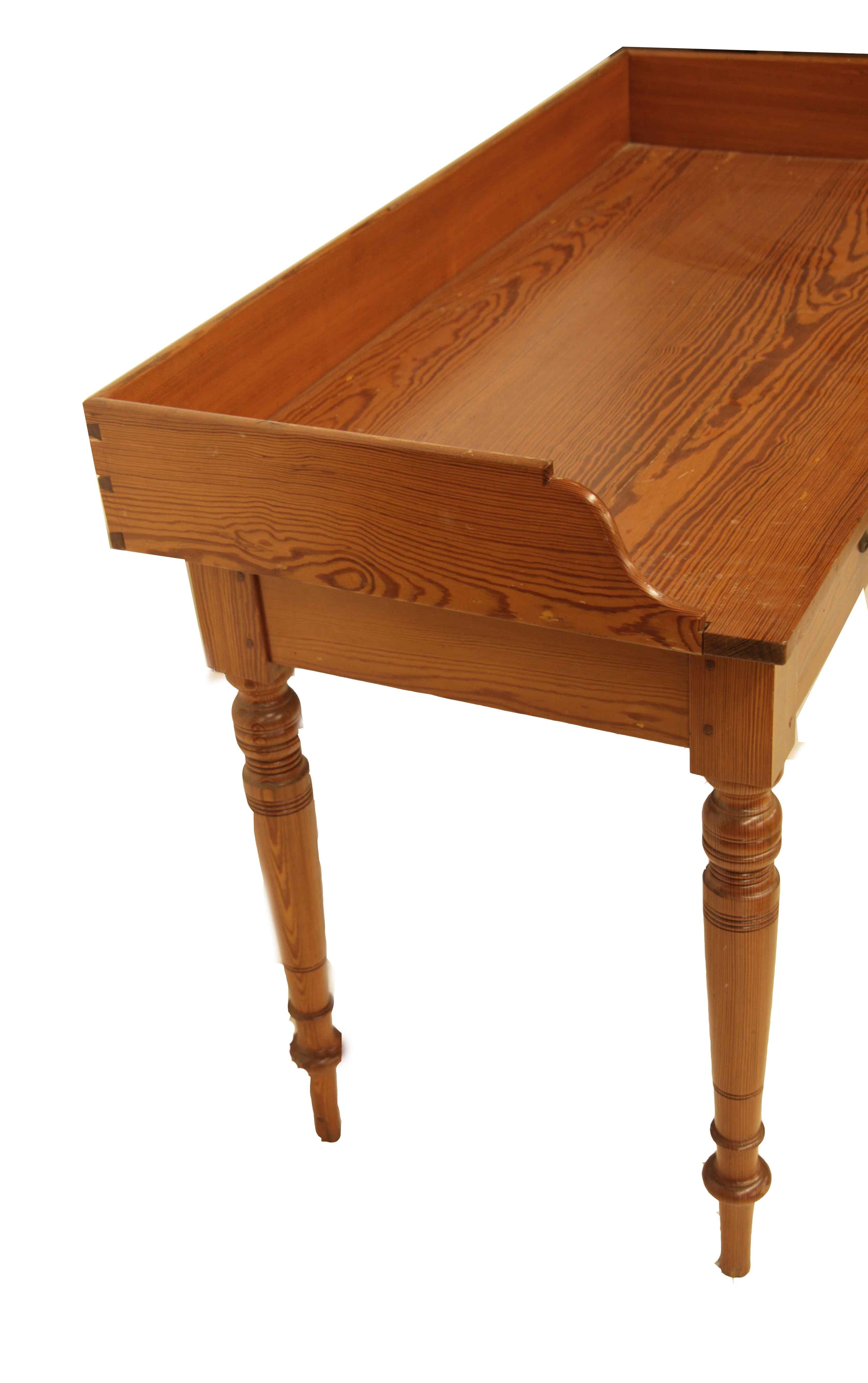 English pine two drawer table in England, they refer to this as ''pitch pine'', here we call it ''heart pine'', by whatever term, it is beautiful wood with bold color and grain. The top has a gallery around the sides and back, two drawers with solid