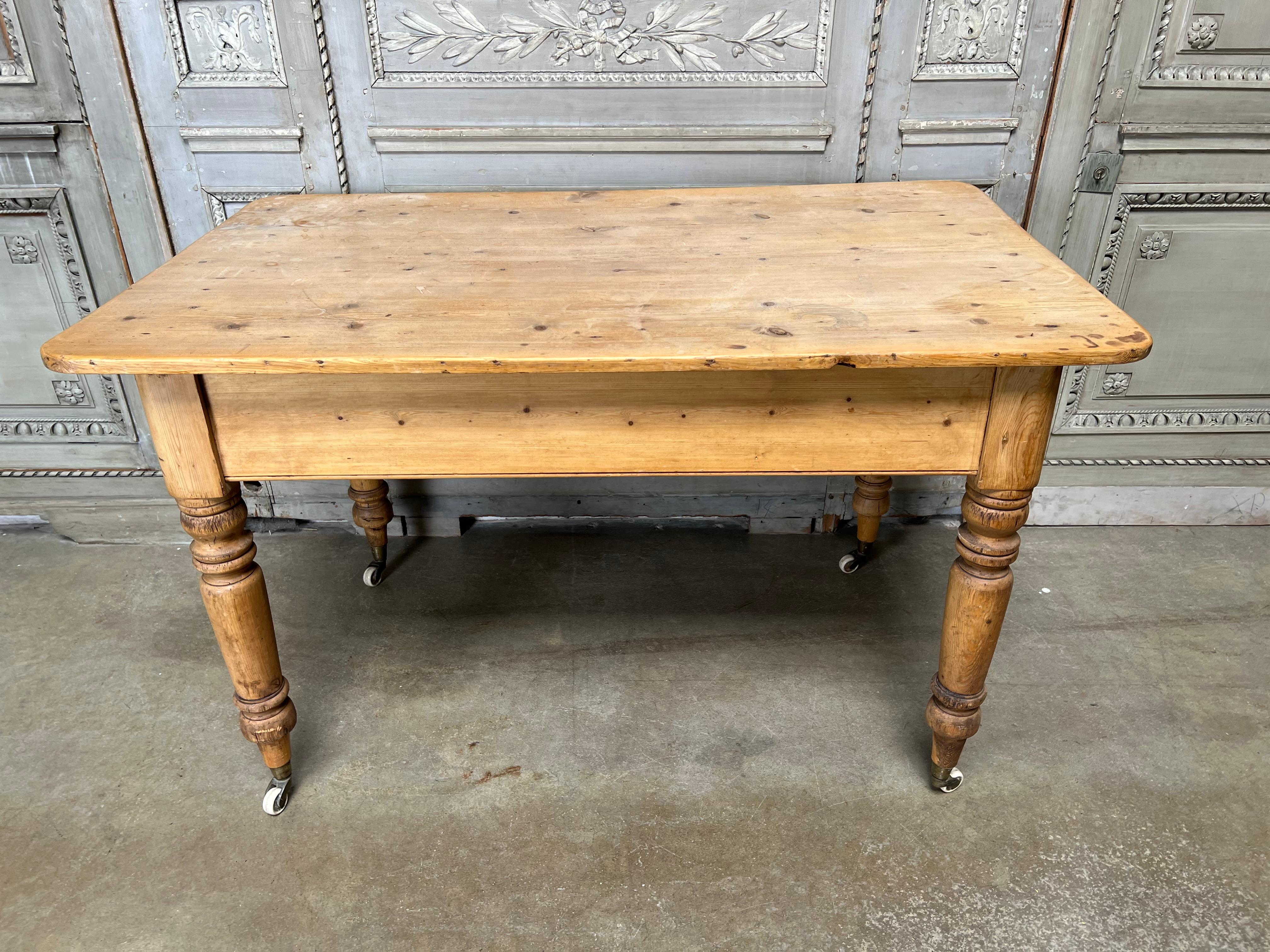 An English Victorian pine kitchen farm table. This table has a drawer at one end and is on brass and porcelain casters. It is an ideal kitchen island and breakfast table.