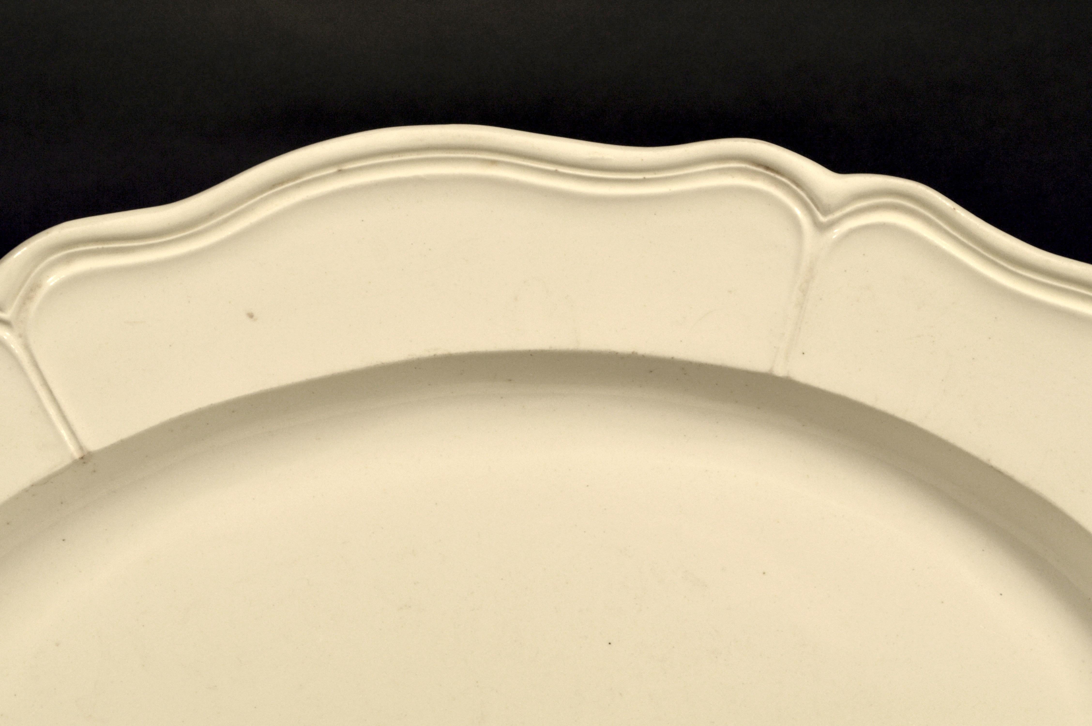 English plain creamware large oval dish,
circa 1770-1785

The large creamware dish has a molded rim with six shaped panels and a slightly raised rim.

Dimensions: 16 1/2 inches x 13 inches x 1 1/2 inches high.