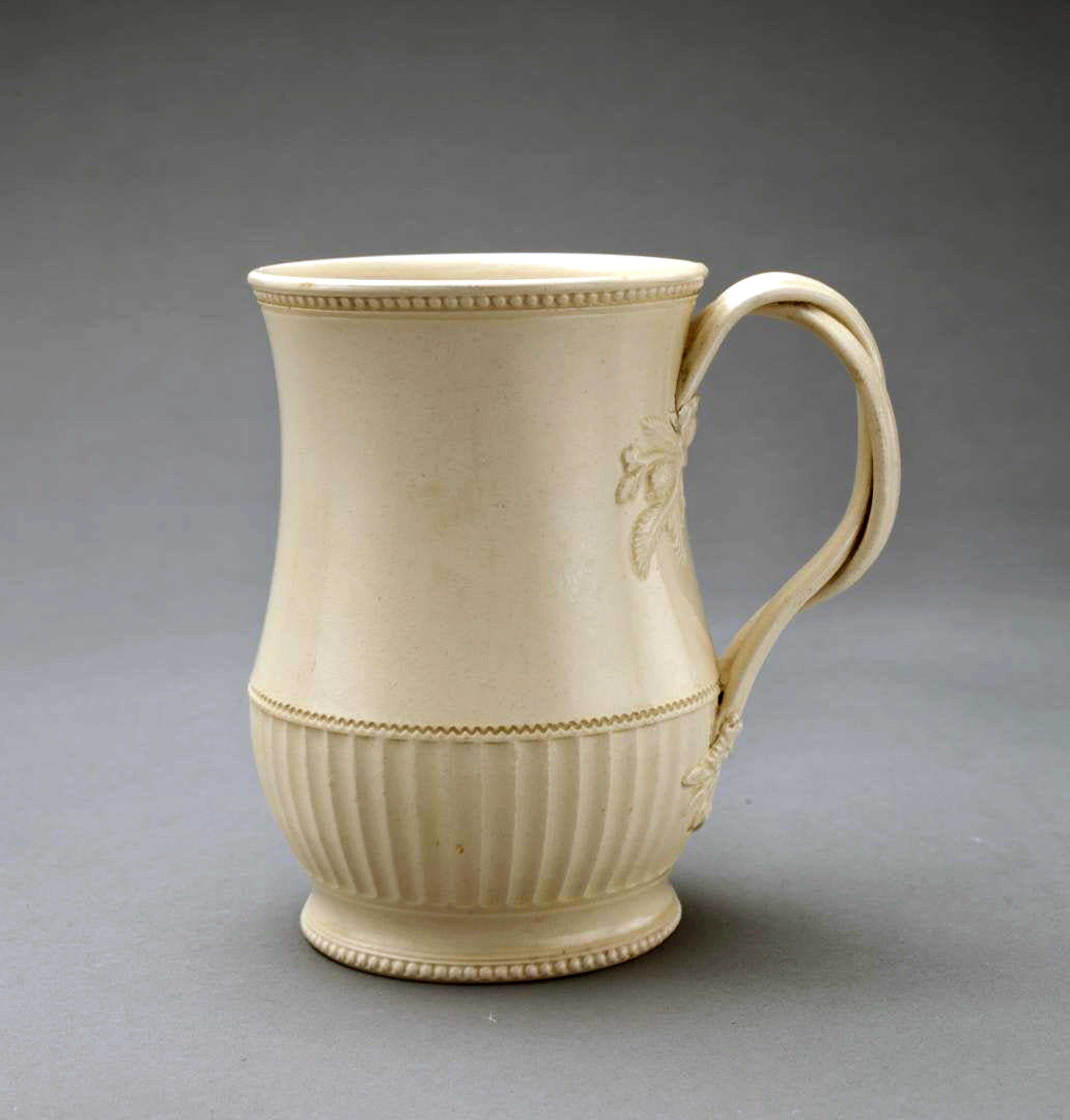 English plain Creamware Tankard,
Leeds,
Circa 1770

A Leeds creamware tankard, of ogee form, its lower third fluted and with beaded rim and foot-rim and with vine-twist handles terminating in flower and leaf sprigs. 

Dimensions: 
5 1/8
