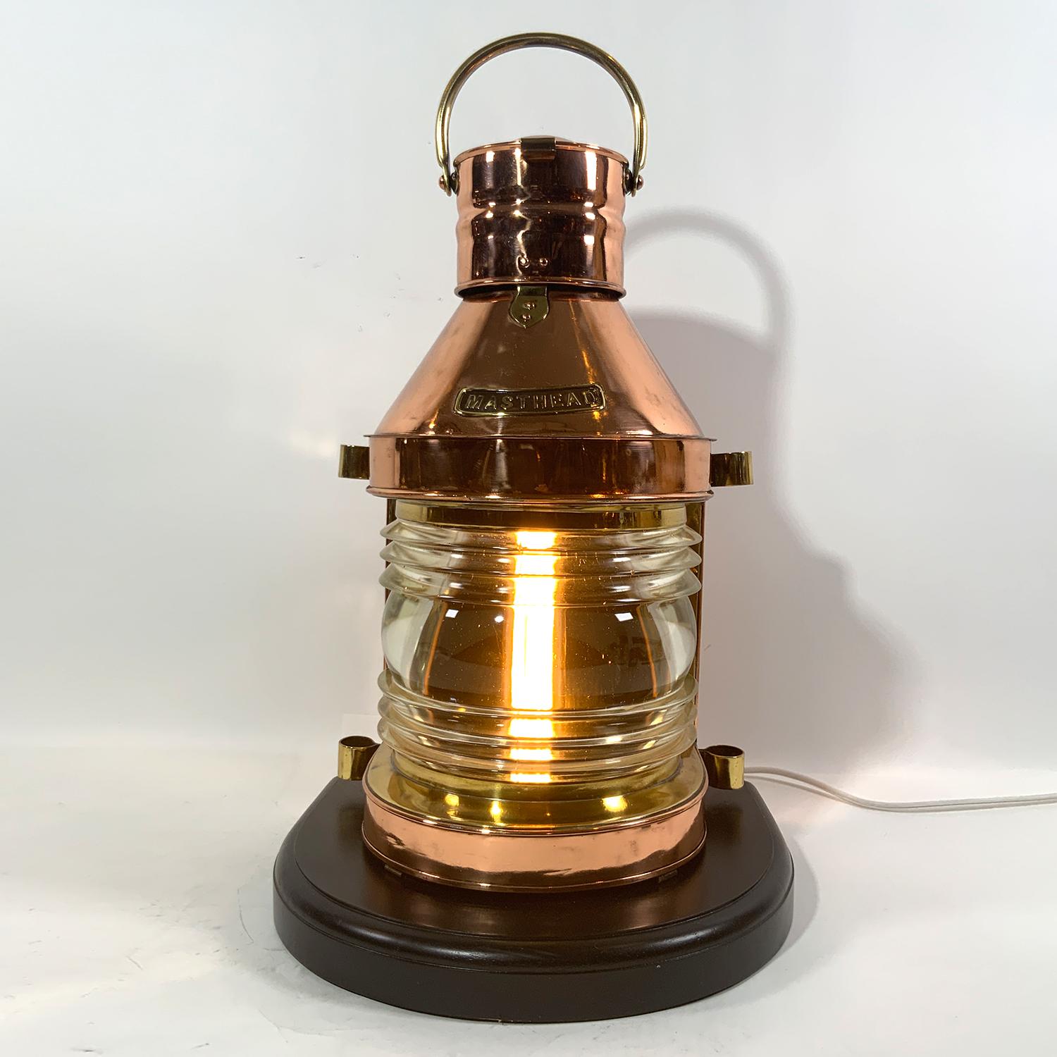 Highly polish and lacquered ship's masthead lantern. With clear Fresnel glass lens. Vented top, brass carry handle. Mounted to a thick mahogany base. Wired for home use. This is an exceptional lantern in very good condition. Circa 1925.