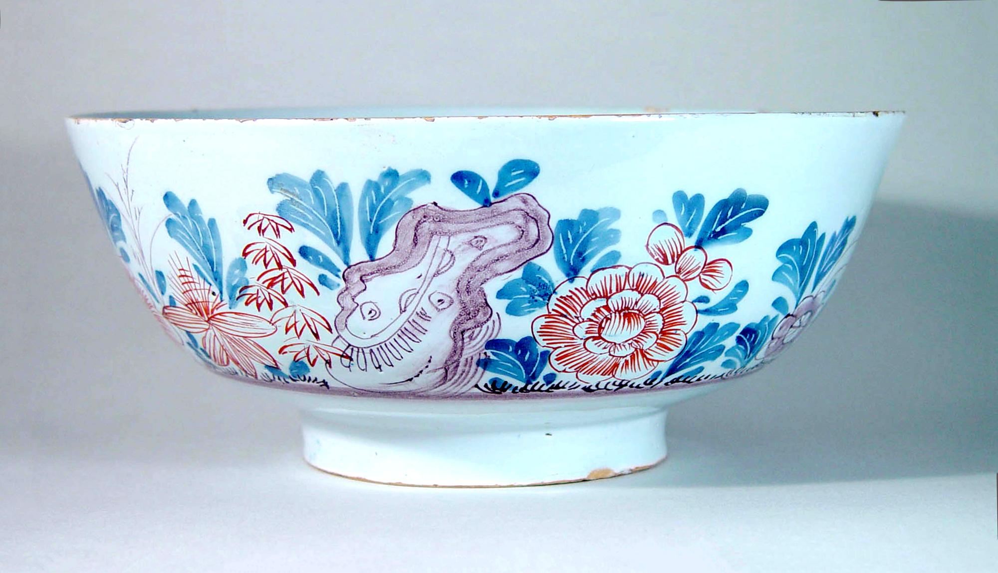Chinoiserie English Polychrome Delftware bowl,
Bristol,
Circa 1760

The bowl with a depiction of Chinoiserie flowers and plants with rockwork in iron-red, blue, and manganese. The scene runs around three-quarters of the bowl. In the central well