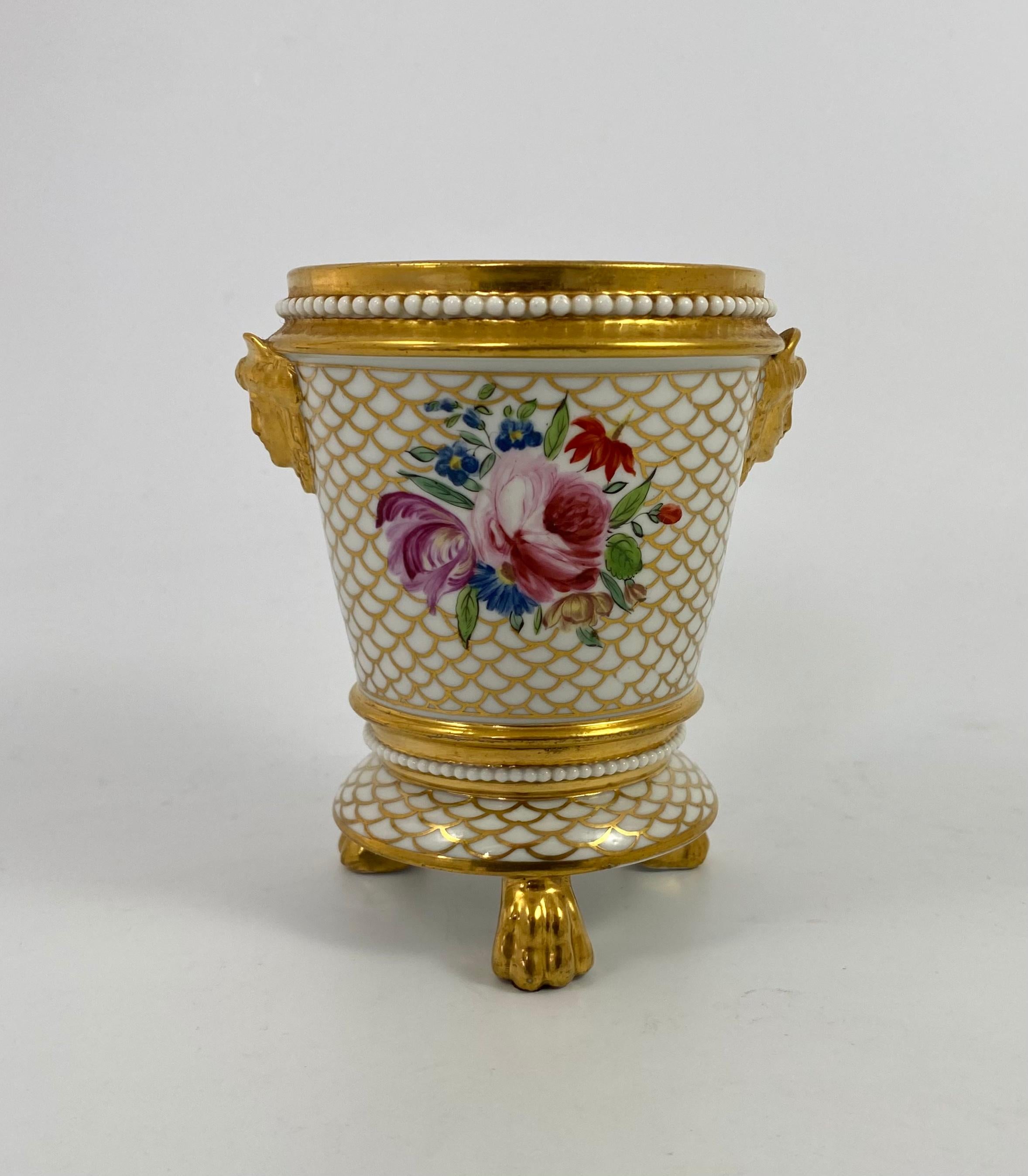 English porcelain cache pot and stand of high quality, c. 1820. The body well painted with sprays of flowers, upon a gilt scale ground, in Spode style. Having a beaded border, and applied with gilt twin mask handles.
The base, similarly decorated,