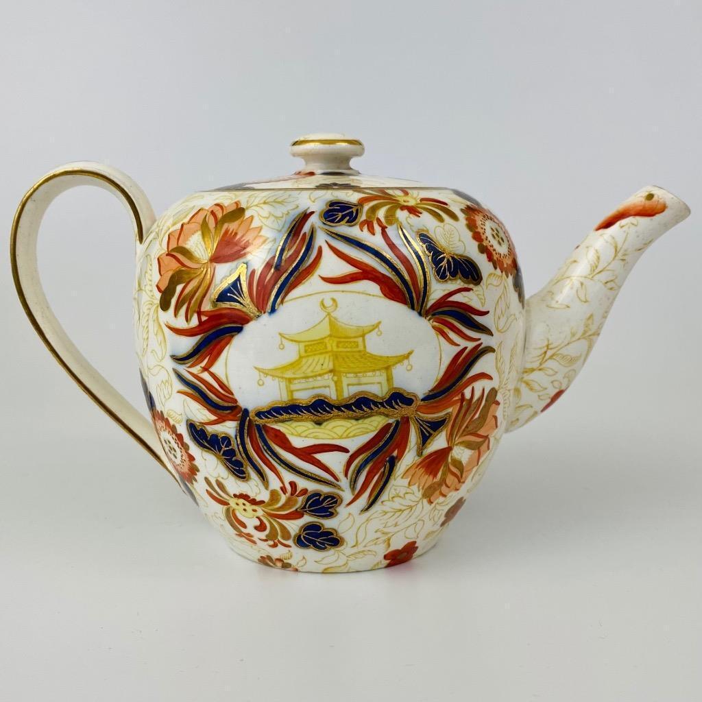 English Porcelain Chinoiserie Imari Teapot
19th Century

The bullet-shaped porcelain teapot is painted with an unusual design with a Chinese pagoda within an oval shaped panel between Imari colored leaves and yellow stems.

Height 4 1/2 inches x 6