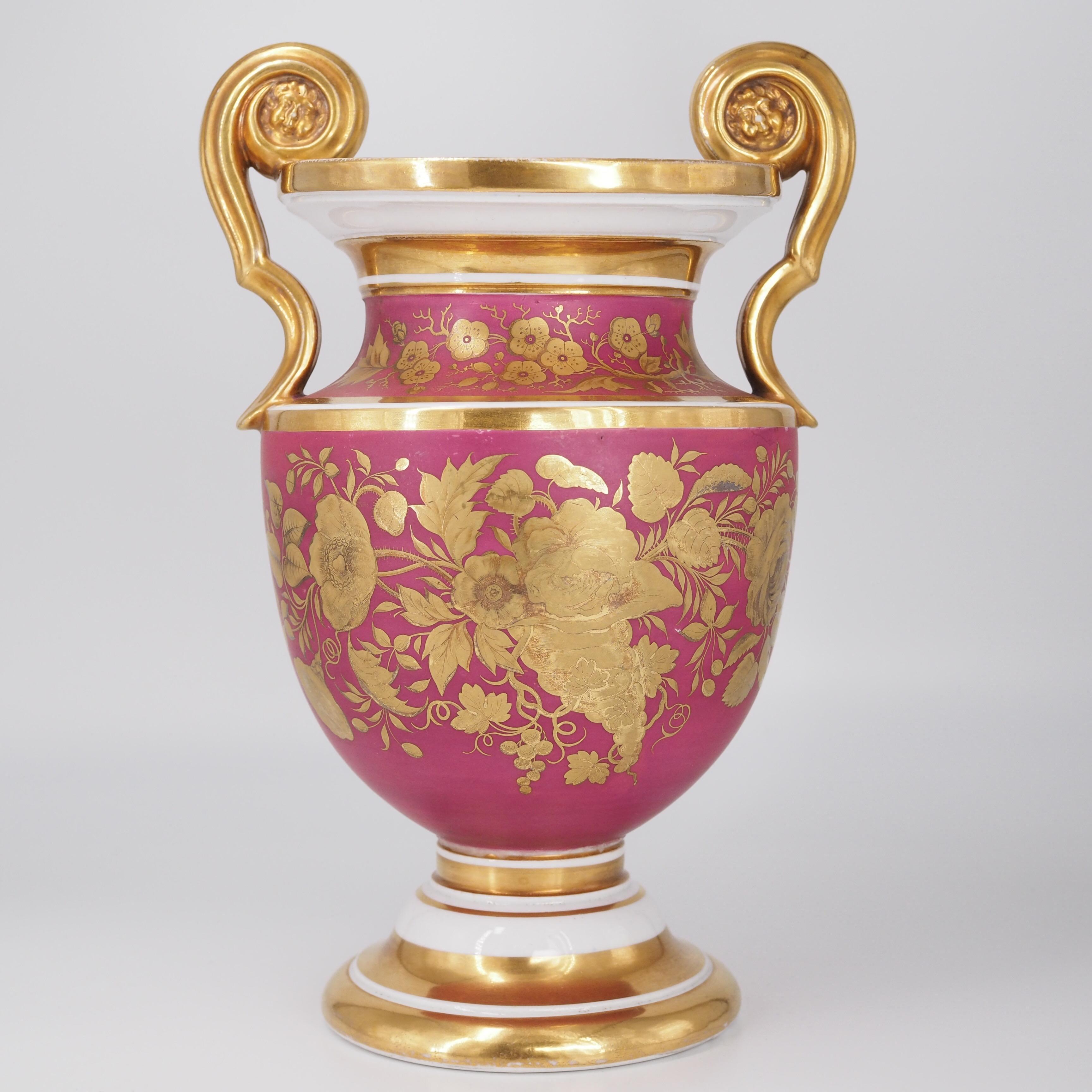 English bone china urn, the form taken from a Greek neck-amphora, the gilt handle terminals with scrolls framing a face, the front with a panel of flowers reserved on a puce ground, the reverse with superb tooled gold flower spray with tooling.
