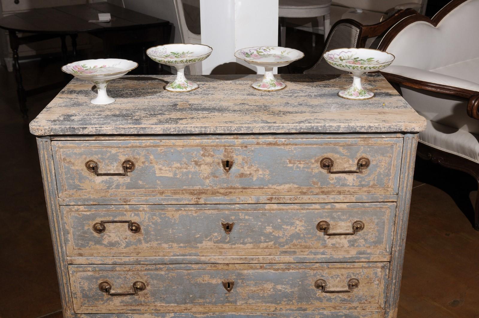 Four English porcelain compotes from the 20th century, with floral decor and gilded trim, priced and sold individually. Attracting our attention with their lovely silhouettes and delicate decor, each of these four compotes features a scalloped edge
