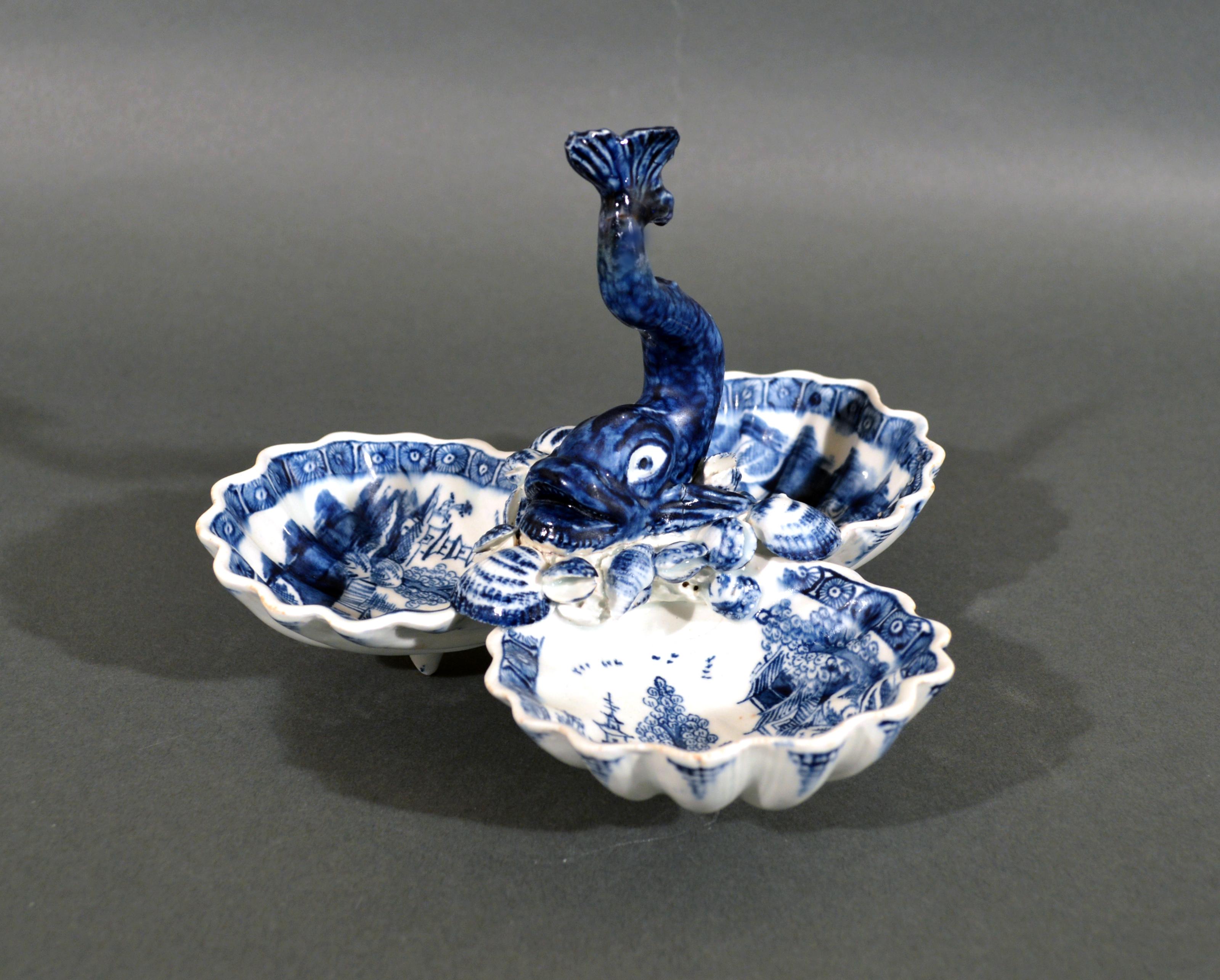 English porcelain dolphin sweetmeat or pickle stand,
Bow factory,
1752-1755

The English soft-paste porcelain sweetmeat stand or pickle stand is painted in underglaze blue and comprising of three shell-shaped dishes, each raised on a conical peg
