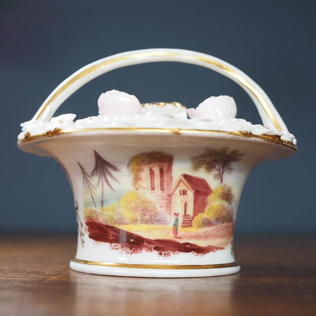 Potpourri basket & lid, well painted with a Romantic landscape to either side with gilt anthemion divider, the upper surface with encrusted daisy & rose heads.

Unmarked, possibly Chamberlain's Worcester, Circa 1825.