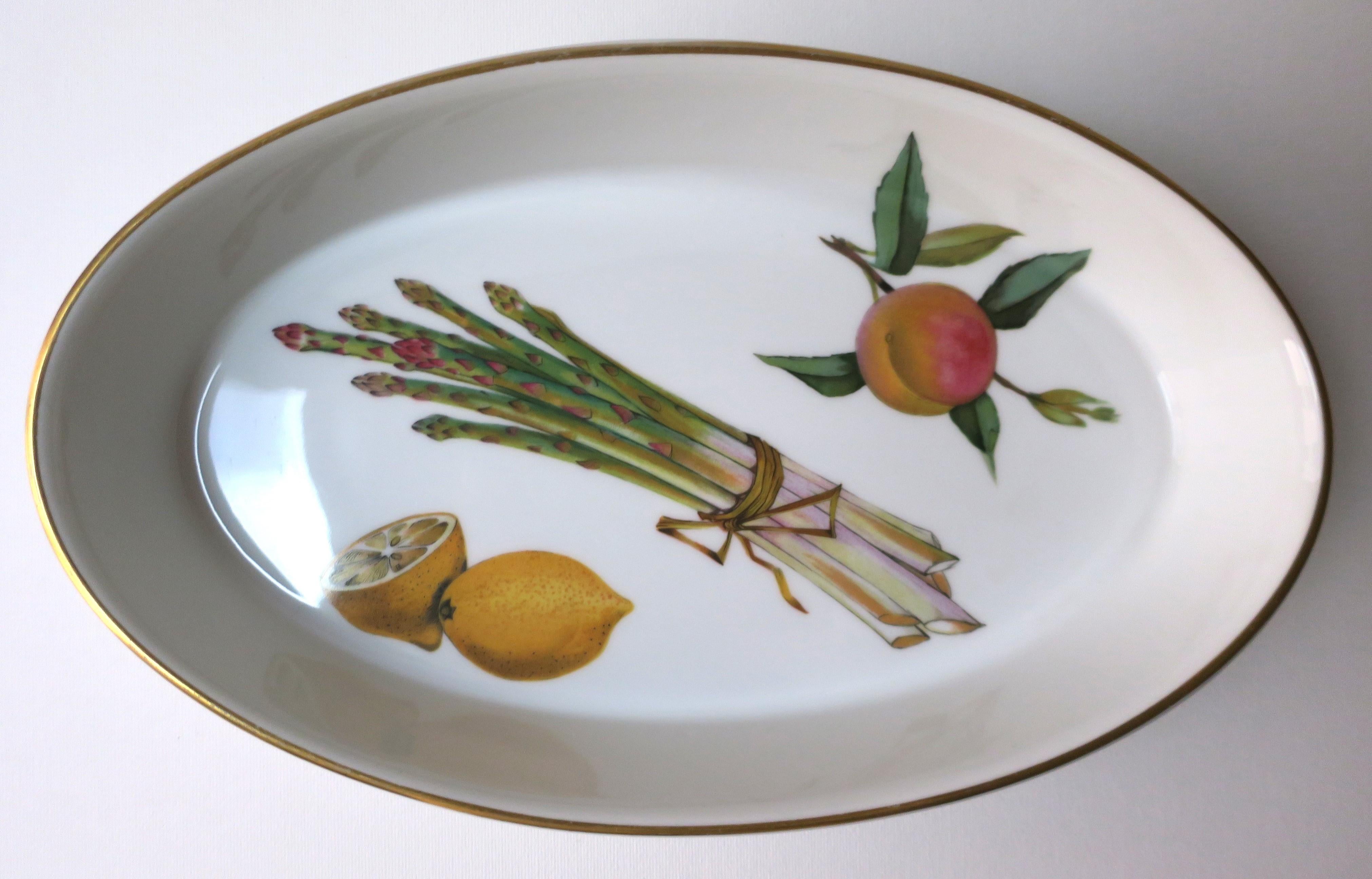 A very beautiful English oval porcelain serving bowl with fruits and vegetables edged in gold, Royal Worcester, circa mid to late-20th century, England. Fuit and vegetable design include lemon, asparagus and peach. Very good condition as shown in