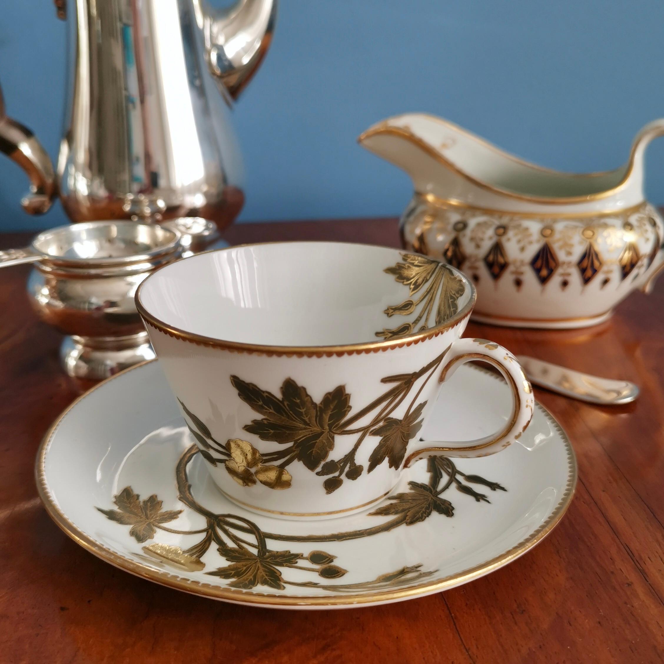 This is a beautiful teacup and saucer made by an unknown factory probably in Staffordshire in about 1875. The cup has a nice clean bucket shape with a loop handle with a gilt motif, and the set is decorated with a beautiful Aesthetic Movement design