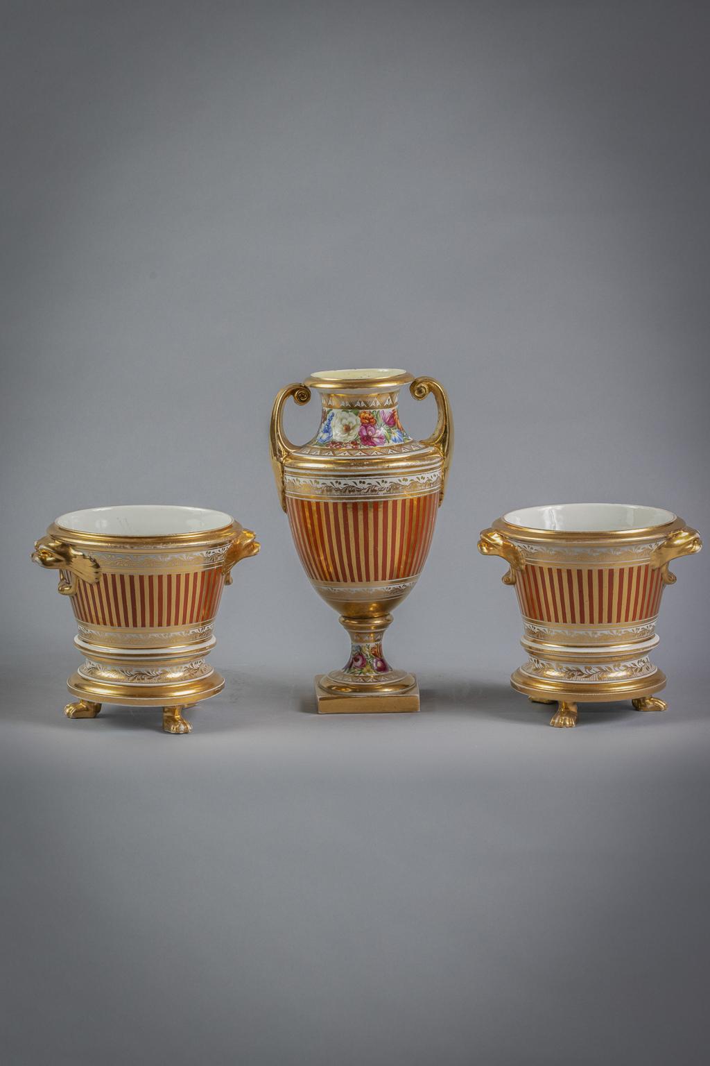 With a central rectangular floral panel on an orange and gilt ground, the cachepots with lion handles and paw footed stands. The two handled vase similarly decorated.