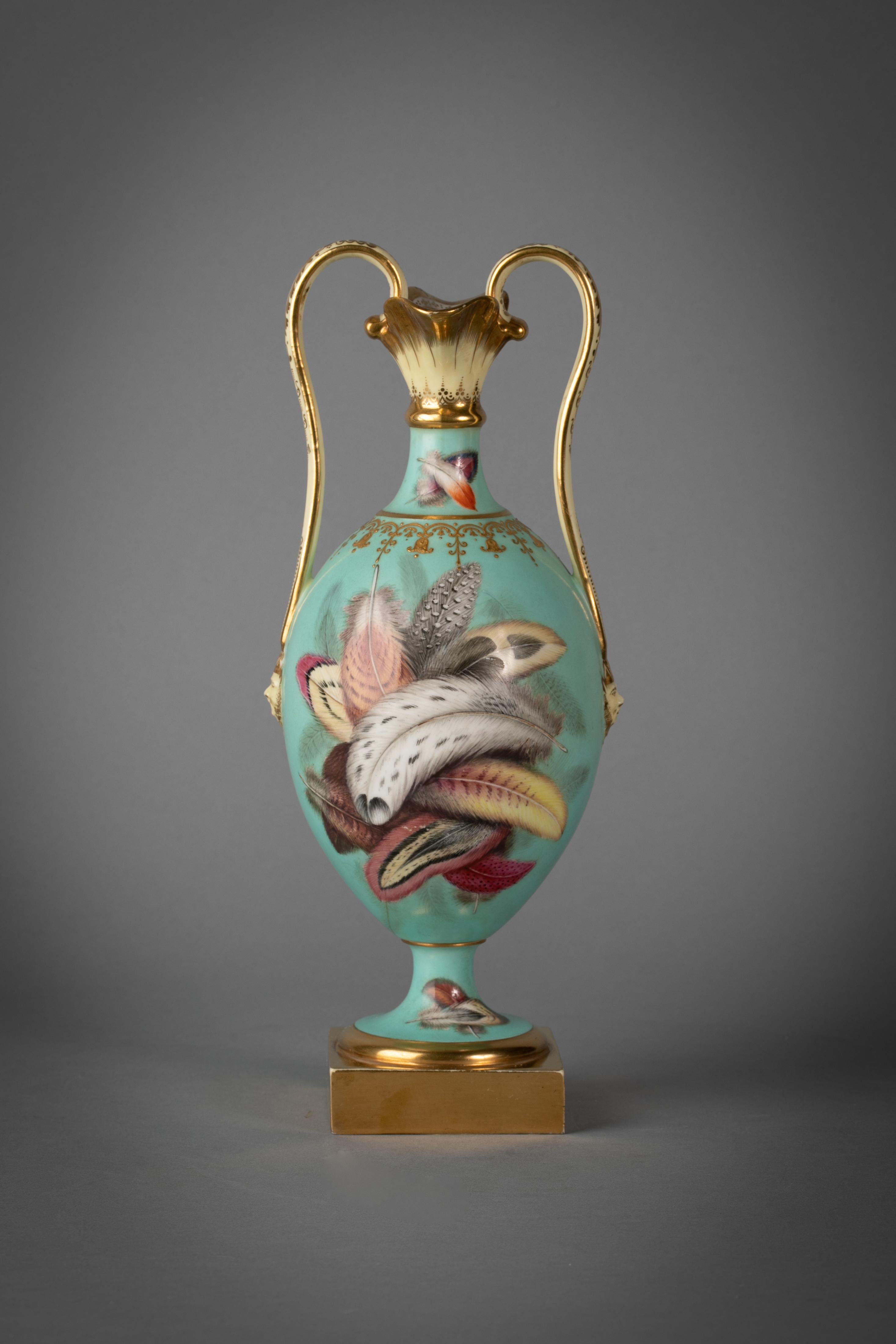 Twin handled double lipped vase. Finely painted with feathers and handles terminating with molded masks.