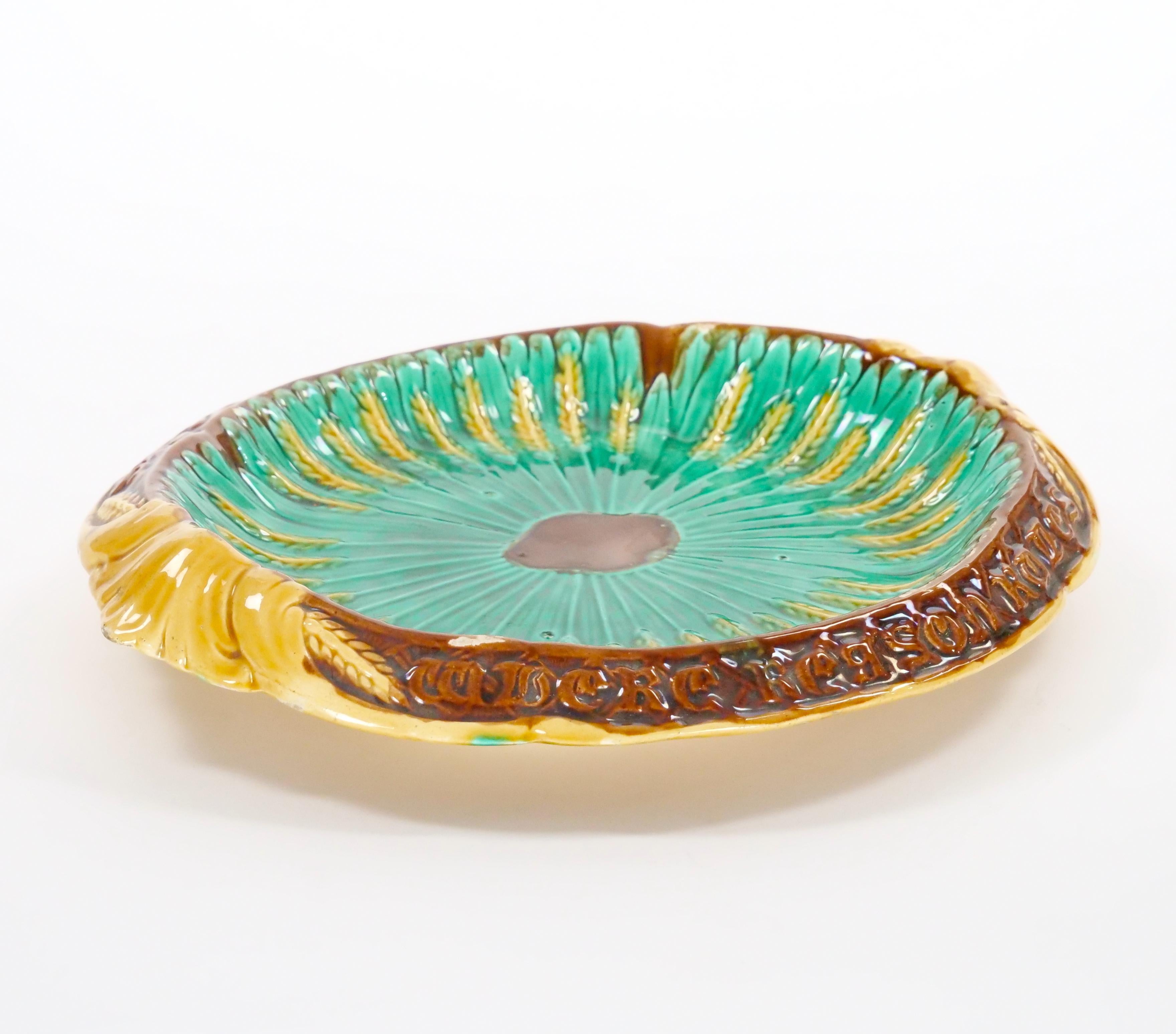 esta exquisita vajilla antigua inglesa de mayólica victoriana es un testimonio de la elegancia y el arte de la época victoriana. Fabricada en porcelana esmaltada, presenta una armoniosa mezcla de tonos verdes, marrones y amarillos que resaltan su