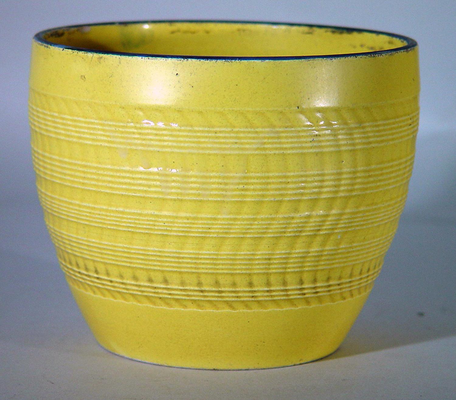 The circular English pottery jardiniere has a yellow ground and has a moulded body with upright wavy lines and bands of straight lines.