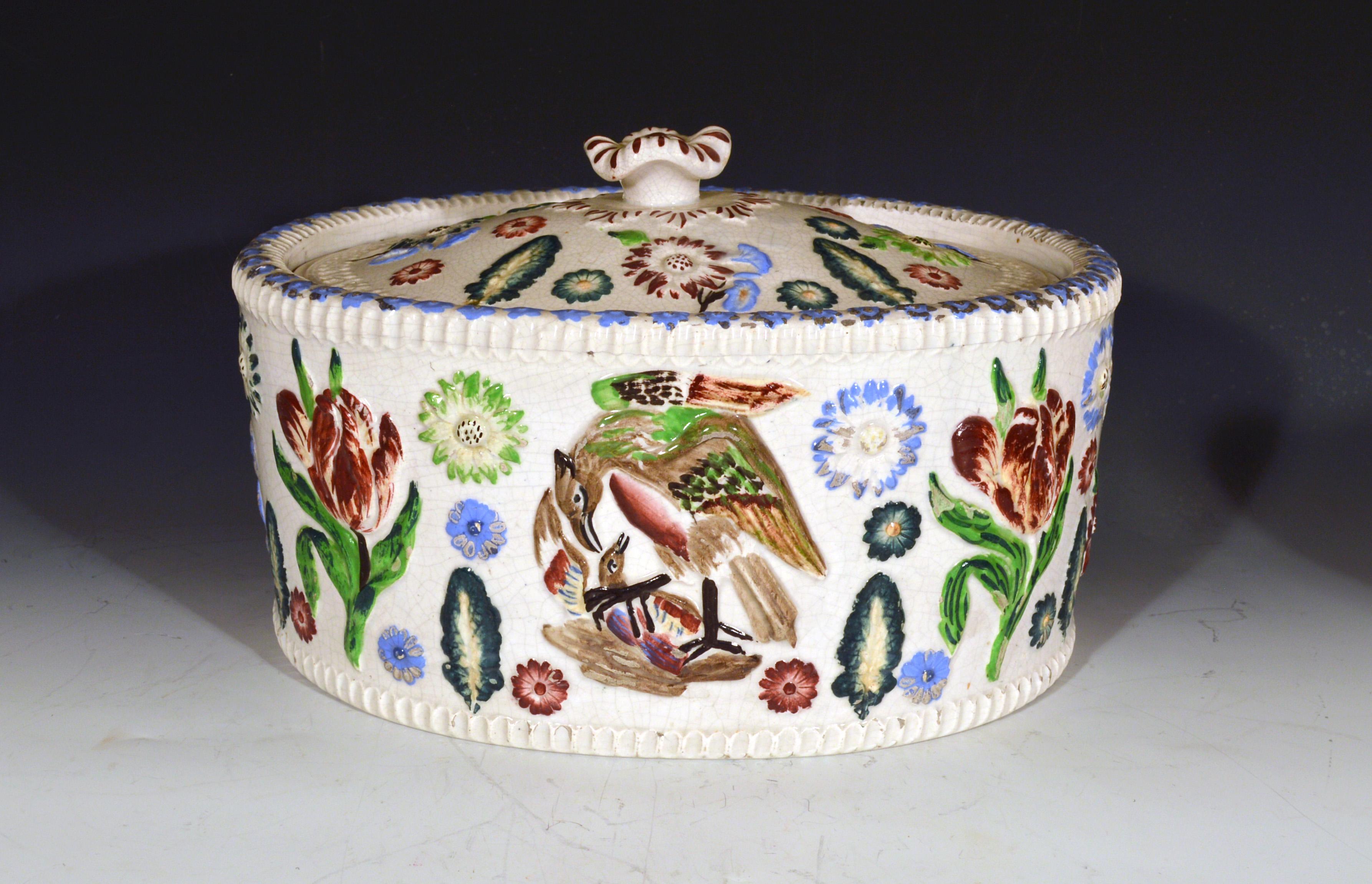 English pottery game tureen,
19th century

The oval game tureen and cover has painted molded mother bird and chick to the center of each side and large molded tulips to each side. Scattered across the body and cover are other molded flowers and