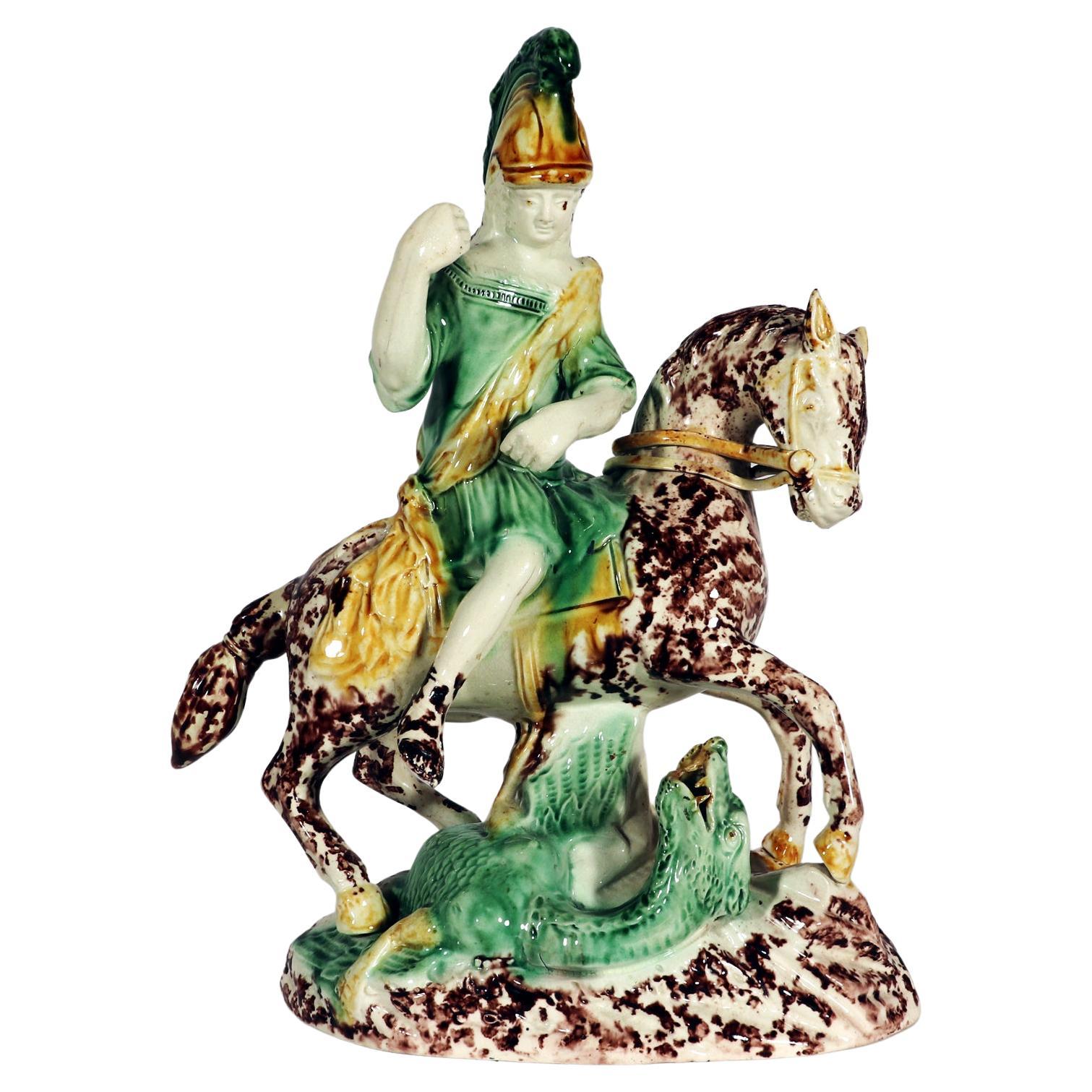 English Pottery Tortoise-shell Creamware Figure of St. George Fighting the Dragon,
Staffordshire, 
Possibly modelled by Enoch and Ralph Wood,
 Late 18th Century. 

The earthenware figure depicts St. George and the Dragon. St. George is on