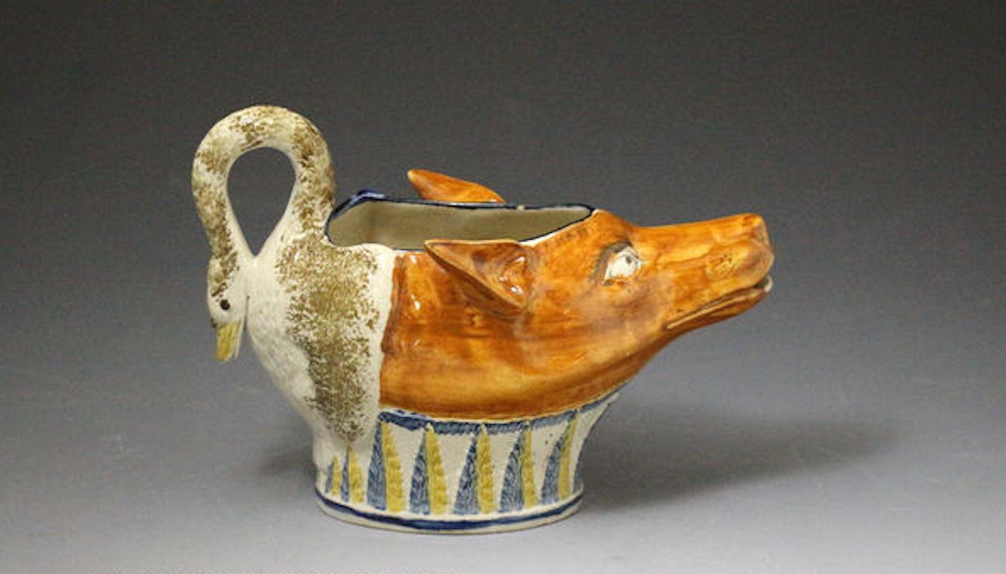 A fine Prattware pottery Fox-Swan zoomorphic sauce boat modelled in the form of a fox's head joined to a swan with the neck serving as the handle. The fox is a rich deep ochre colour and the swan a sponge decorated soft brown. The base is decorated