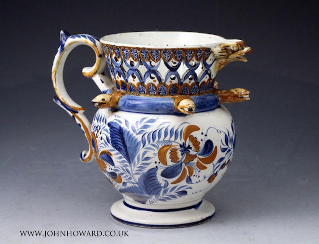 An excellent example of a puzzle jug hand-decorated in Prattware colours. The jug has interesting quality details such as the dolphin head spout, smiling snakes head nossles and an elaborate gallery border with acanthus leaves in relief.

Medium: