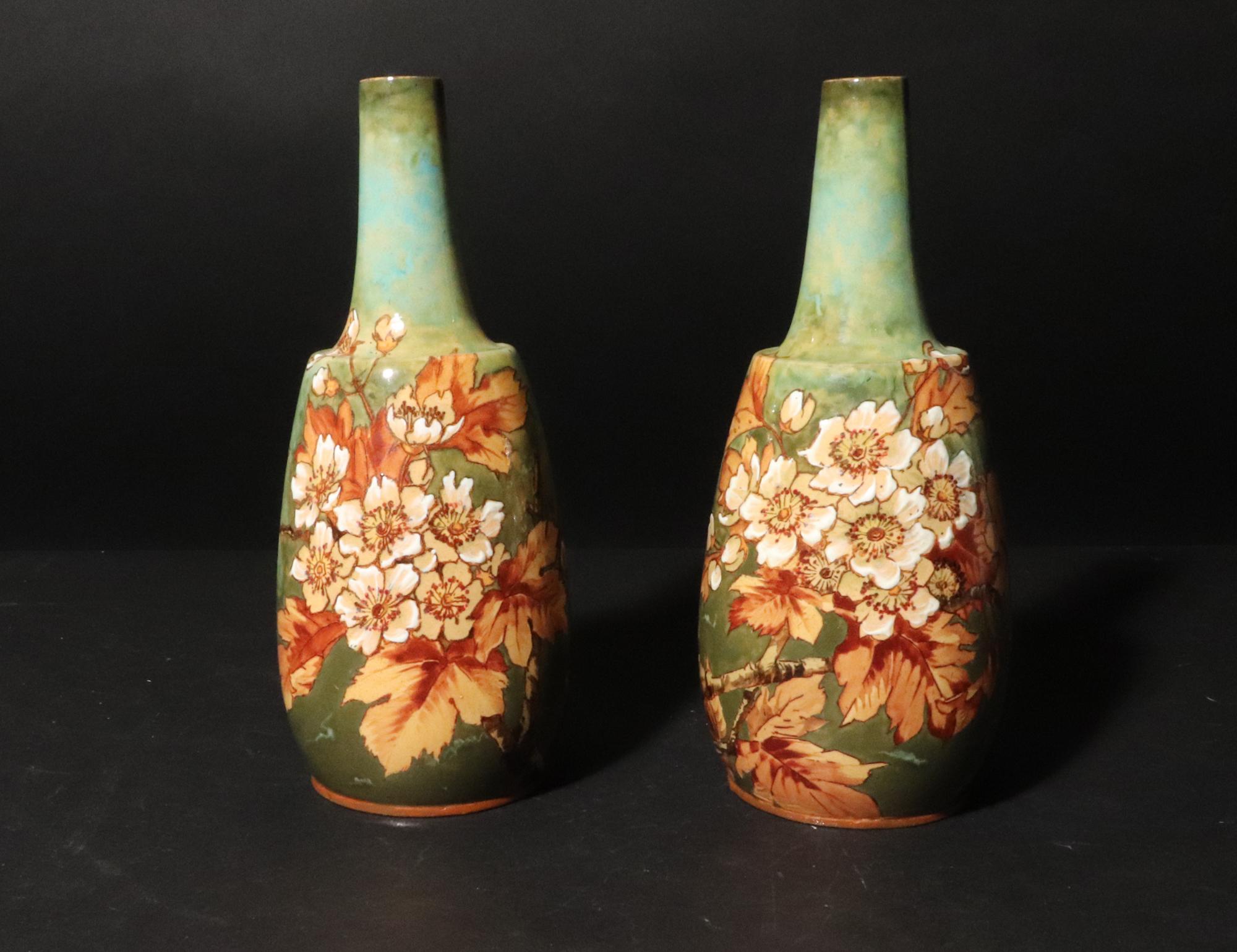 Vasi in ceramica inglese decorati con fiori e foglie, 
Douton Lambeth,
1870s-80s

I vasi di ceramica a forma di mallet sono dipinti a mano con foglie marroni e fiori bianchi su una superficie di  terra verde.

Marchio: il numero 1240 accanto a un