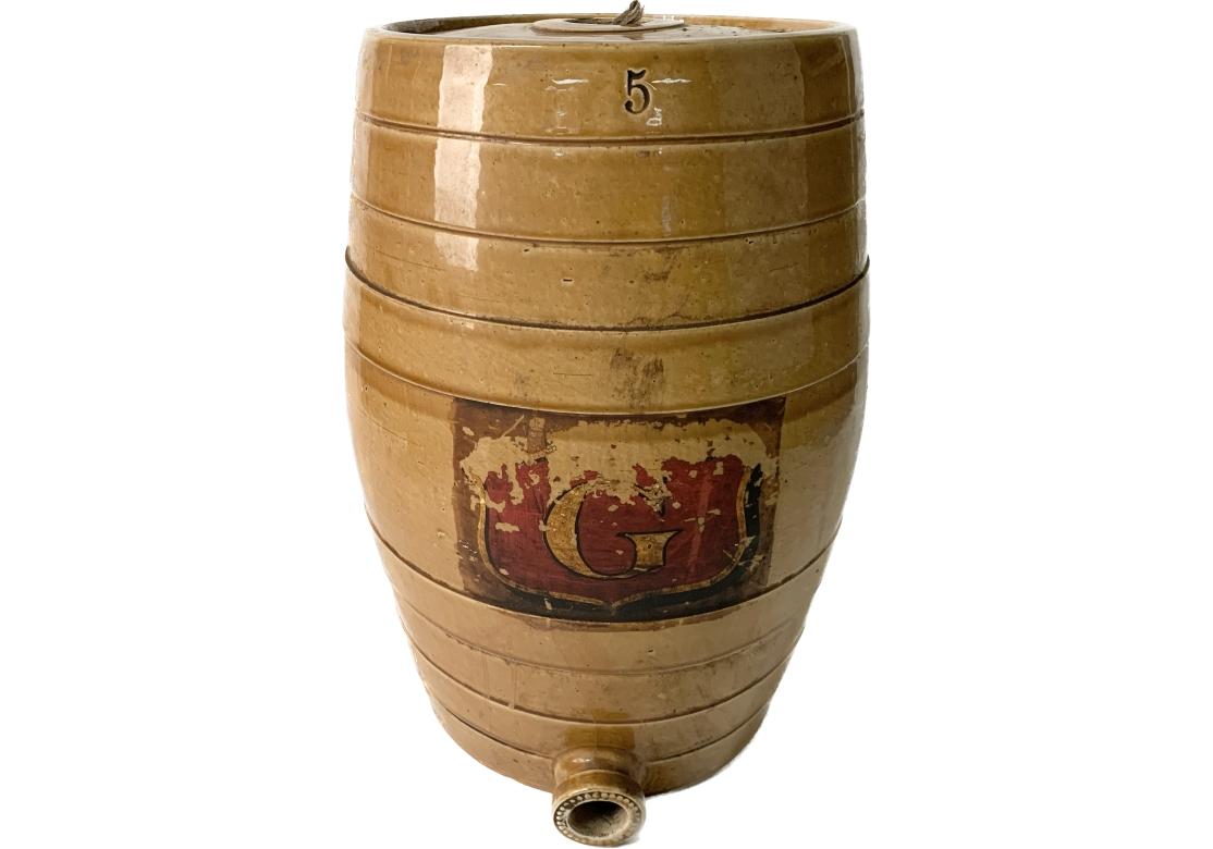 English 5 gallon stoneware barrel with hand painted letter G within a cartouche, cork sealed top and bead decorated bottom spout in a beautiful honey glaze finish with rings. Incised logo for Powell Bristol.
Dimensions: 12 1/2