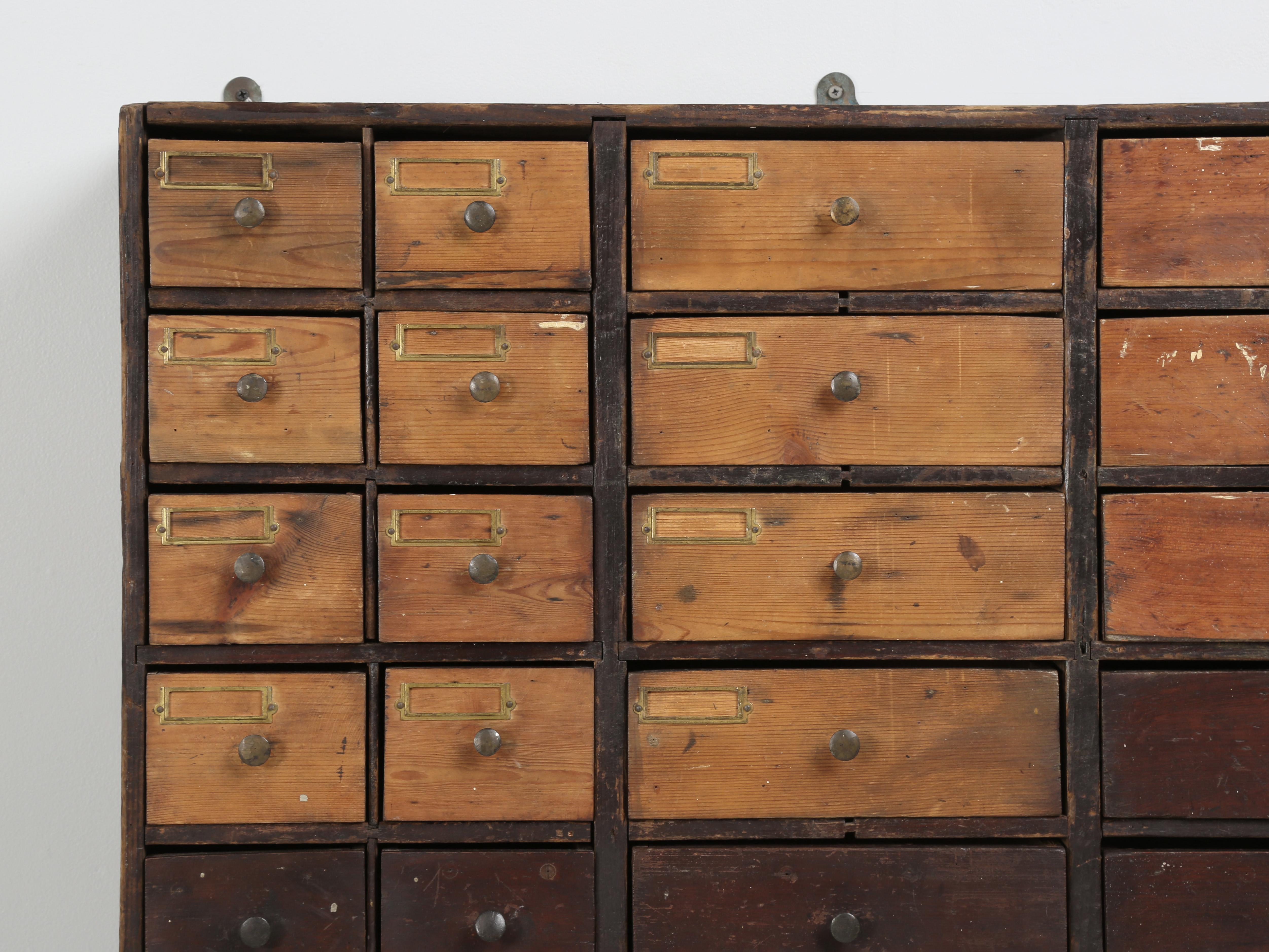 Antique English Hardware store cabinet, or they might have called it in England; a bank of drawers and in this instance, that would mean 56-hand-made drawers. The tell-tail sign of its history and age are nails, that are attached to the bottom left