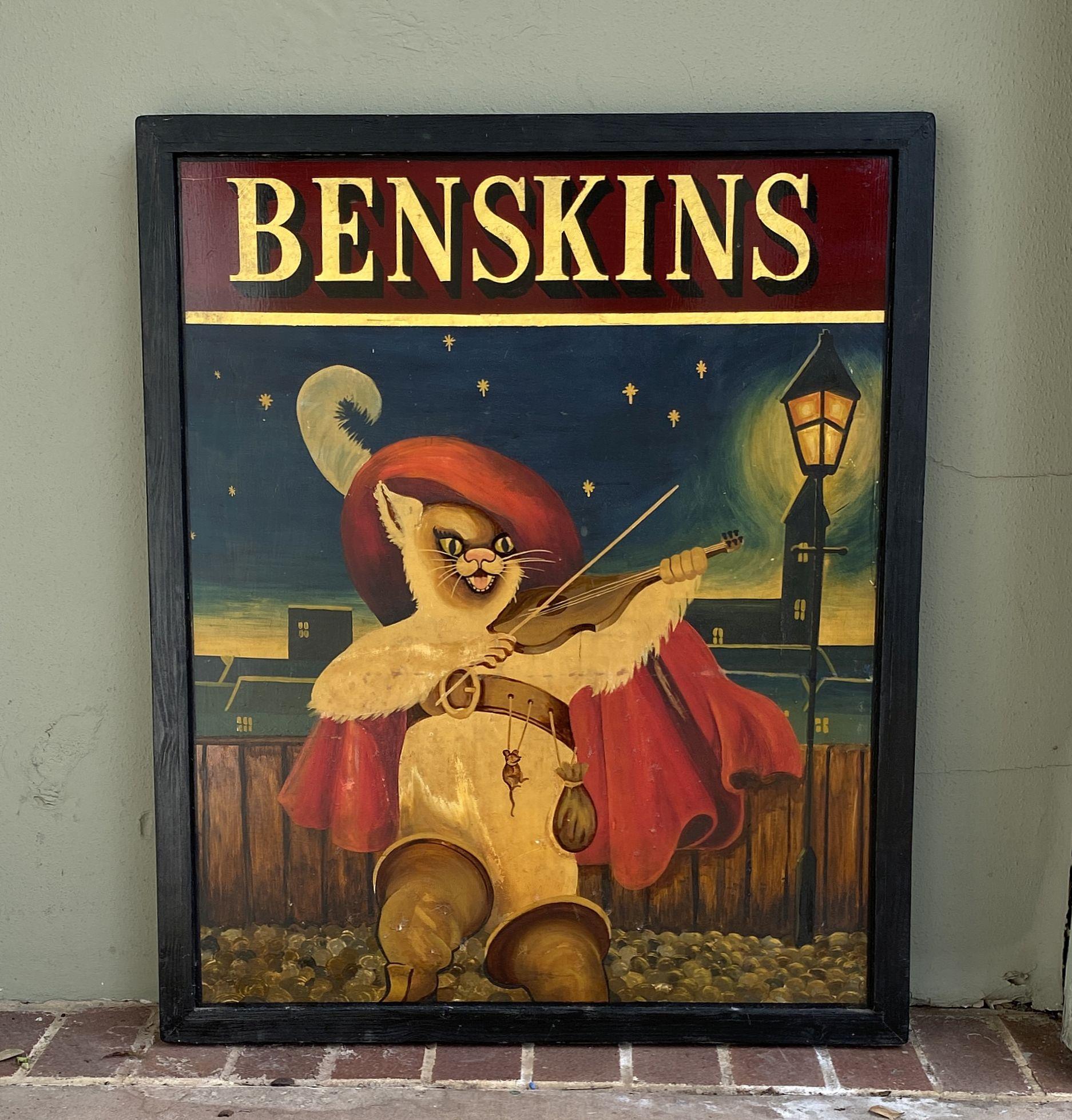 Ein authentisches englisches Pub-Schild (einseitig) mit dem Gemälde einer Geige spielenden Katze - aus dem beliebten Märchen Der gestiefelte Kater - im Licht einer nächtlichen Straßenlaterne mit dem Titel: Benskins.

Ein sehr schönes Beispiel für