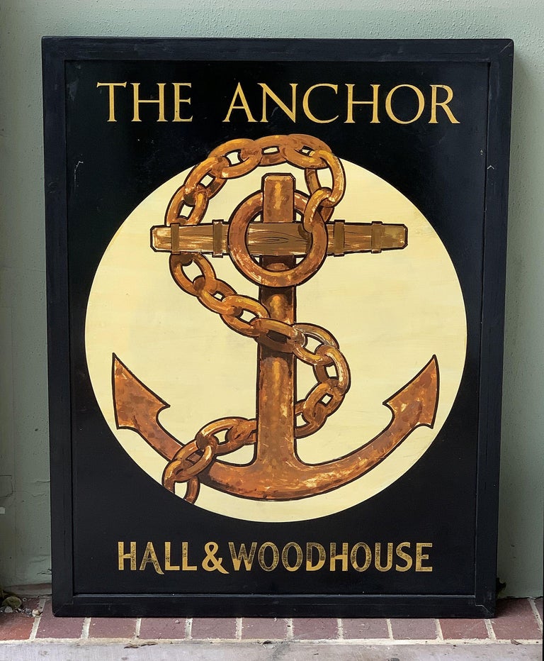 An authentic English pub sign (one-sided) featuring a painting of a ship's anchor superimposed upon a light-colored circle, entitled: The Anchor.

Marked: Hall & Woodhouse

Hall and Woodhouse is a British regional brewery founded in 1777 by