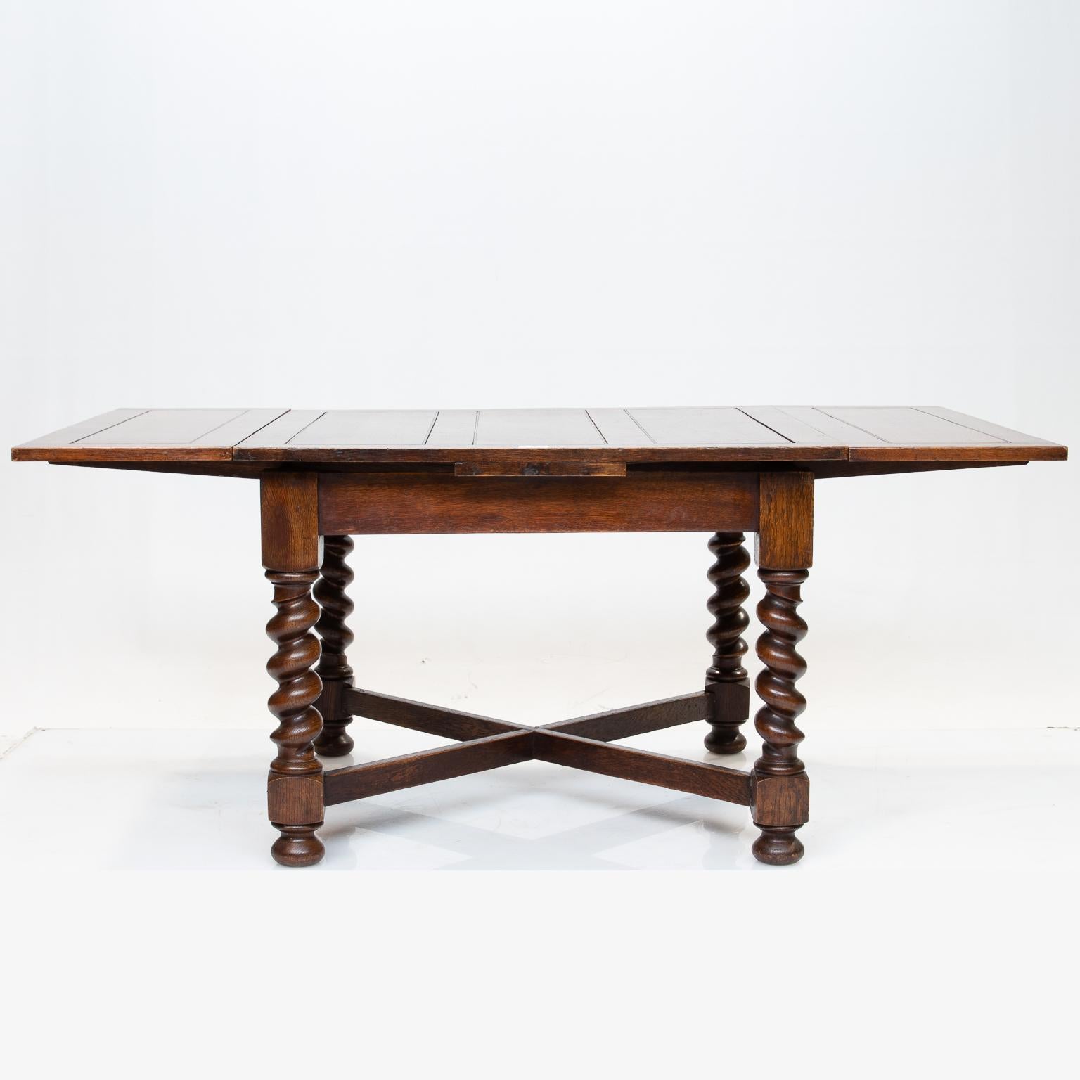 English pub table with draw ends and panel style top. This pub table is made from English oak. The top and draw ends fit very well when fully extended. The legs are in a twist and bun feet. An x-stretcher connects the four legs which add strength.