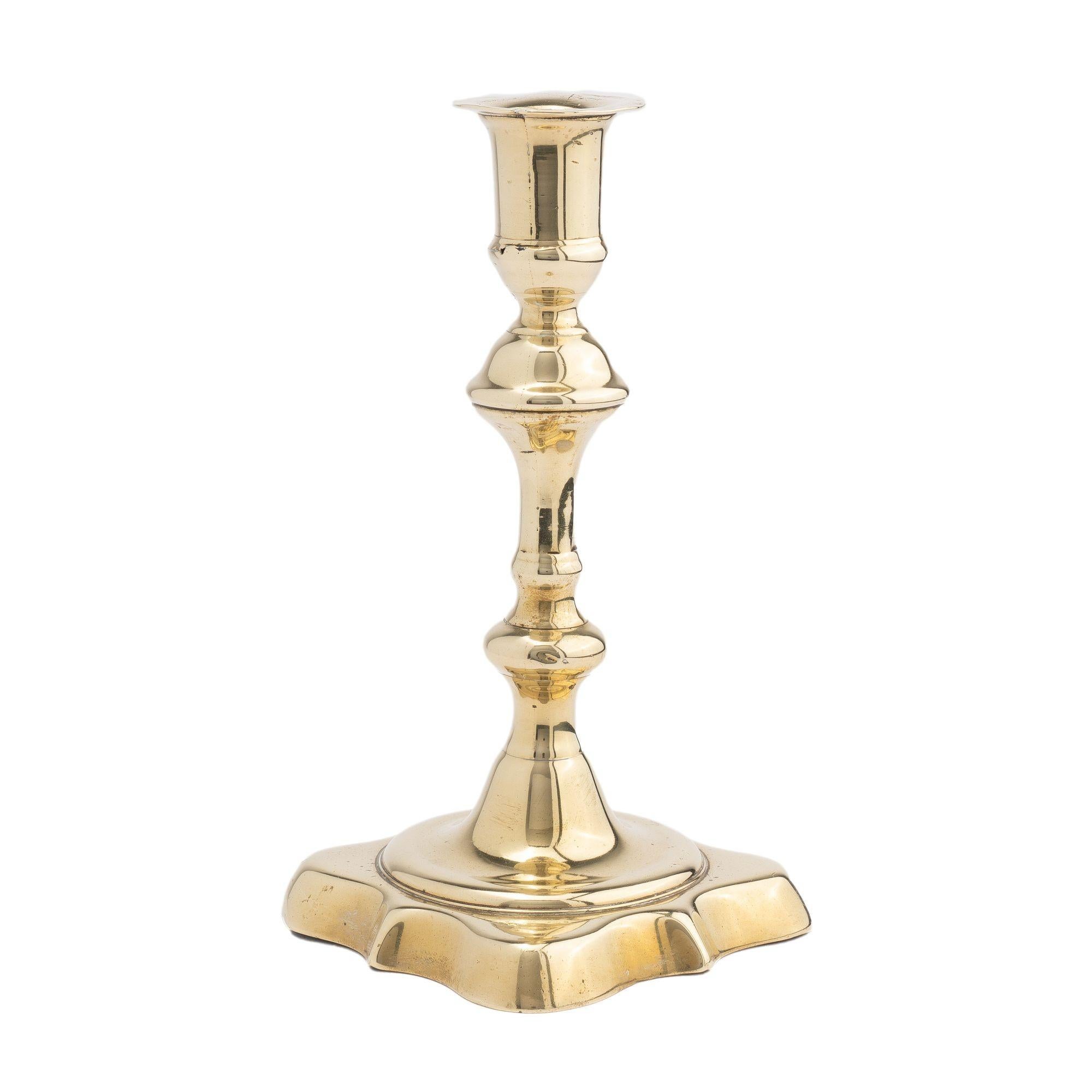 Queen Anne candlestick with shaft cast in two parts cast with the bobeshe and knob below the candle cup and a secondary knob above the base. The base was cast separately and peened to the assembled shaft. The raised lobed base is defined by a