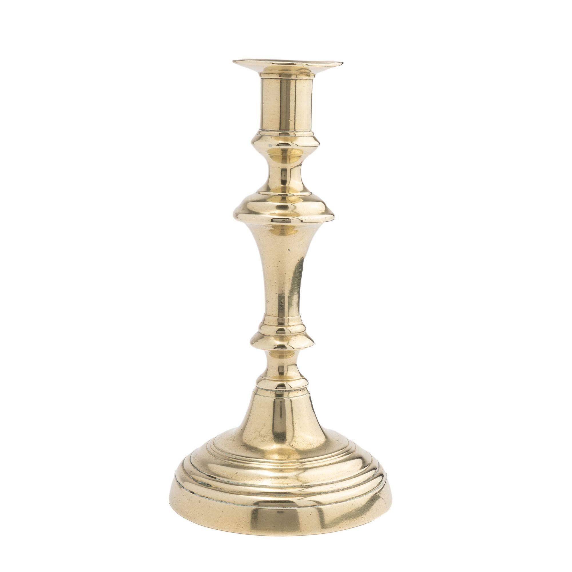 Cast brass circular domed base Queen Anne candlestick with knob stem and internal push up candle ejector.

Birmingham, England, circa 1770.