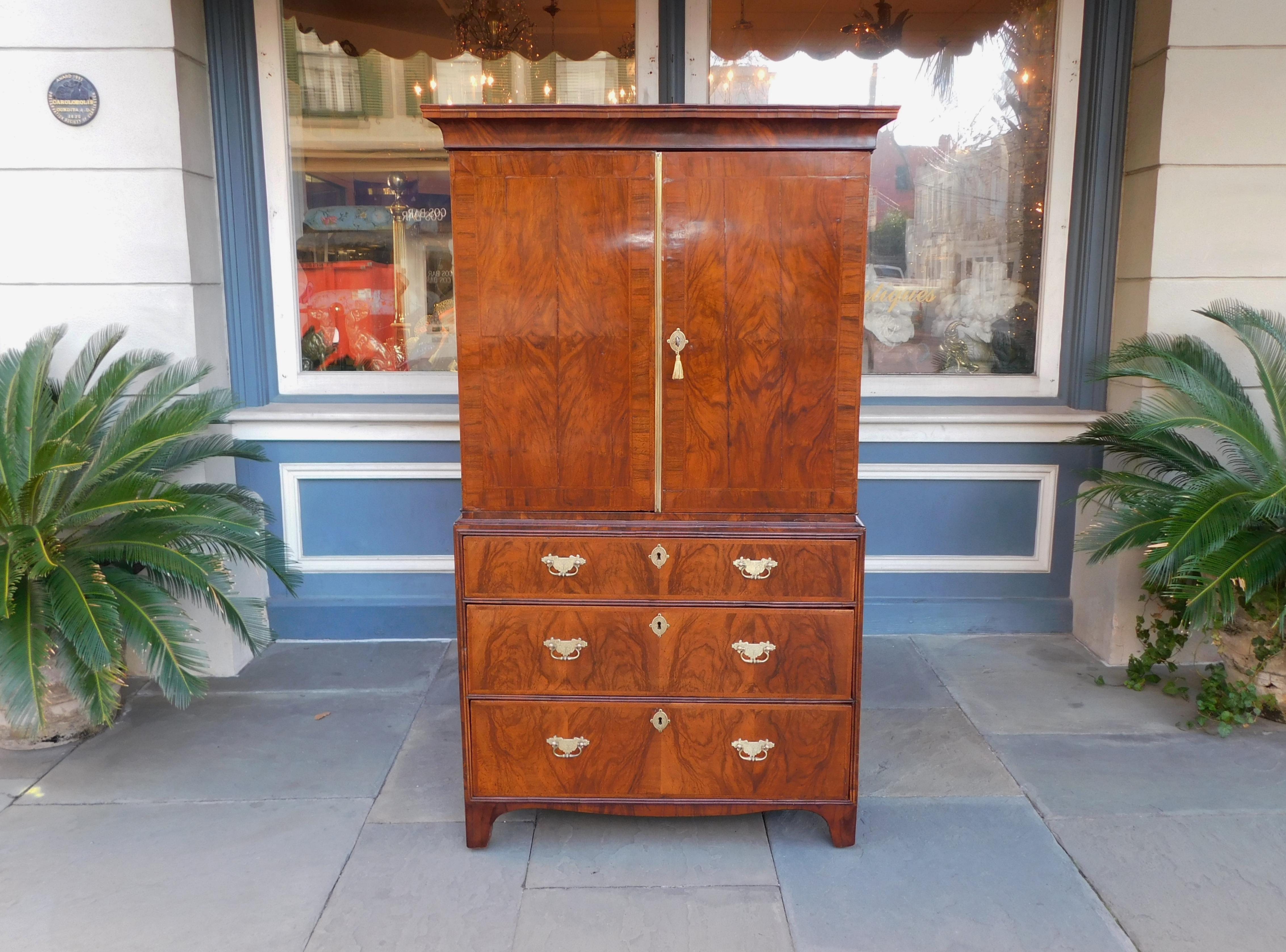 English Queen Anne burl walnut linen press with a carved molded edge cornice, flanking book matched hinged doors revealing fitted interior drawers, original brasses with interior locks and key, three graduated lower drawers, craved scalloped skirt,