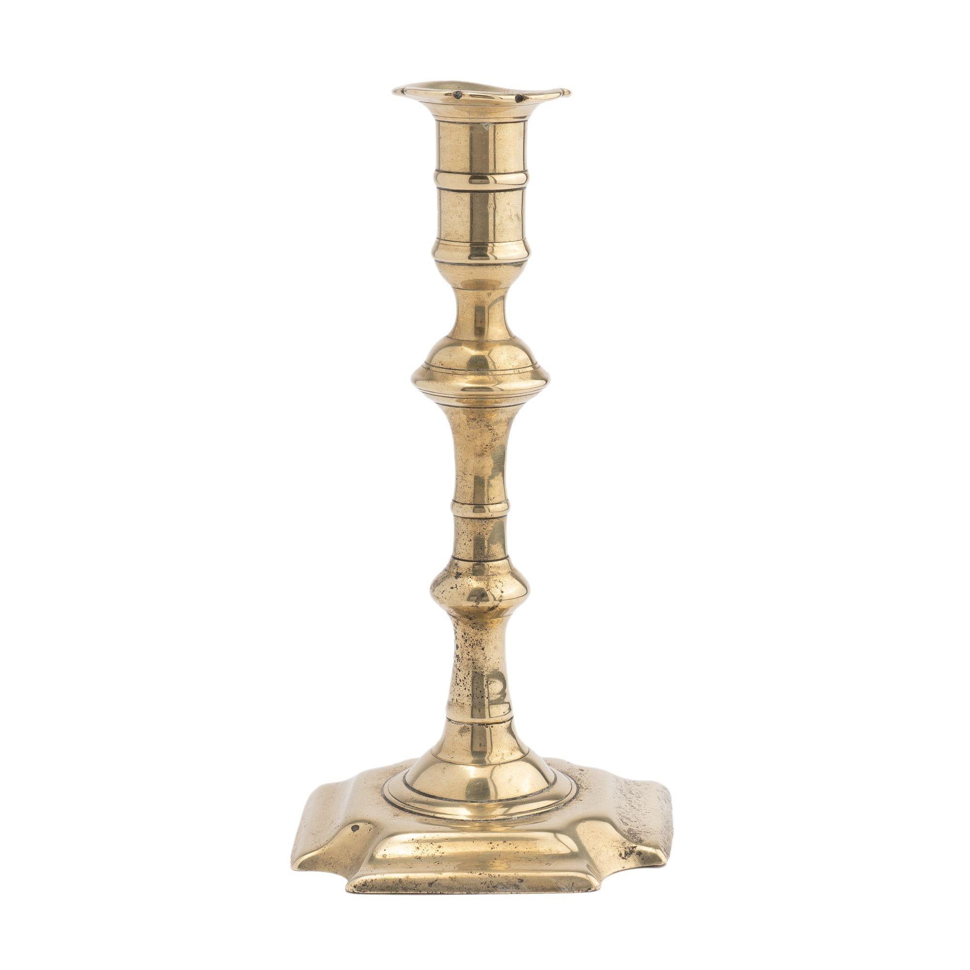 Core cast brass Queen Anne baluster shaft candlestick. The candle shaft, candle cup, and scolloped edge bobeshe is peened to a shallow square base with cove cut corners.

Birmingham, England, circa 1740-60.