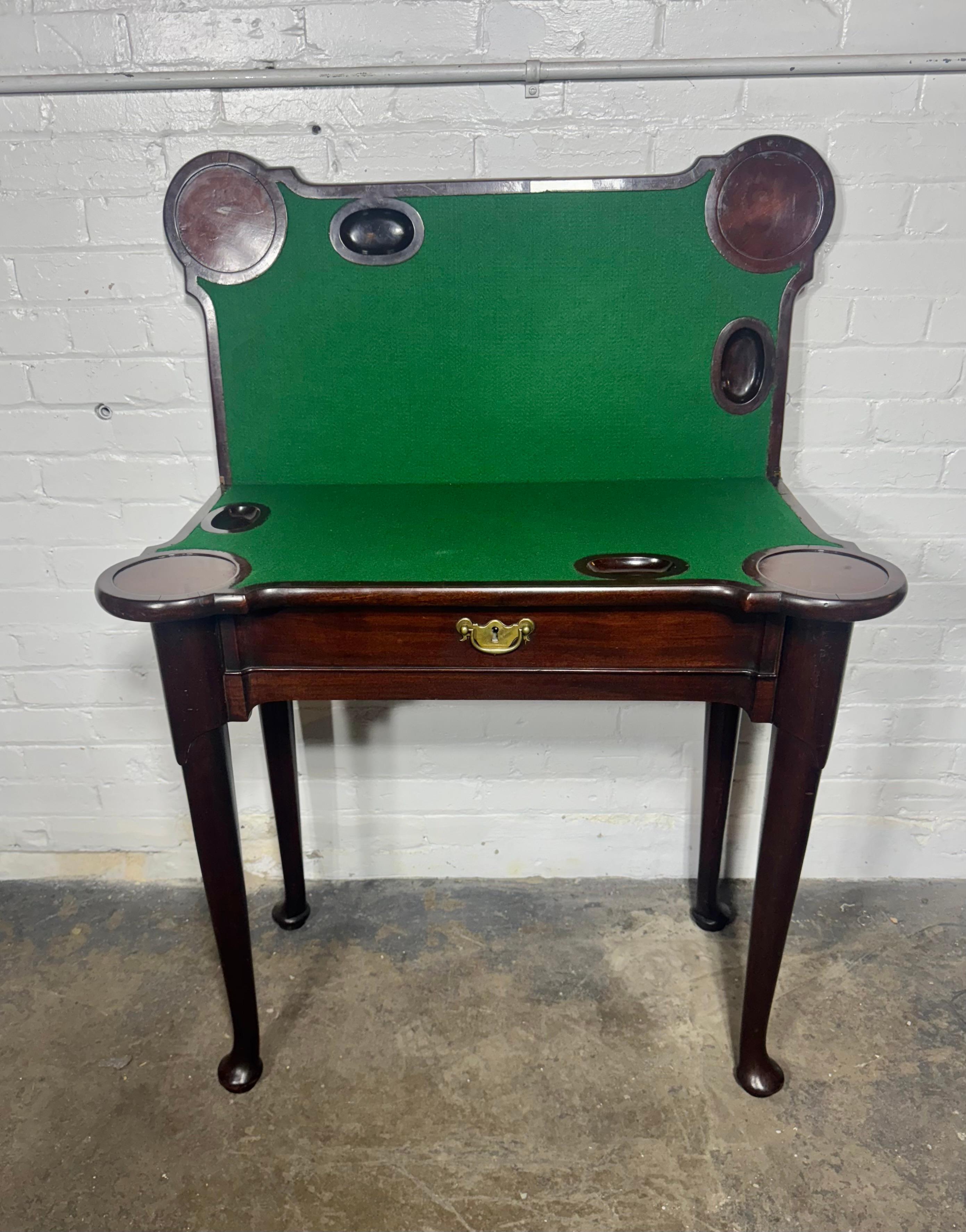 Queen Anne concertina action flip top game table. The table is designed with lieu pockets and turreted porringer corners constructed of mahogany and matched mahogany veneers . The gaming surface is covered with a replaced green baize. The flip top