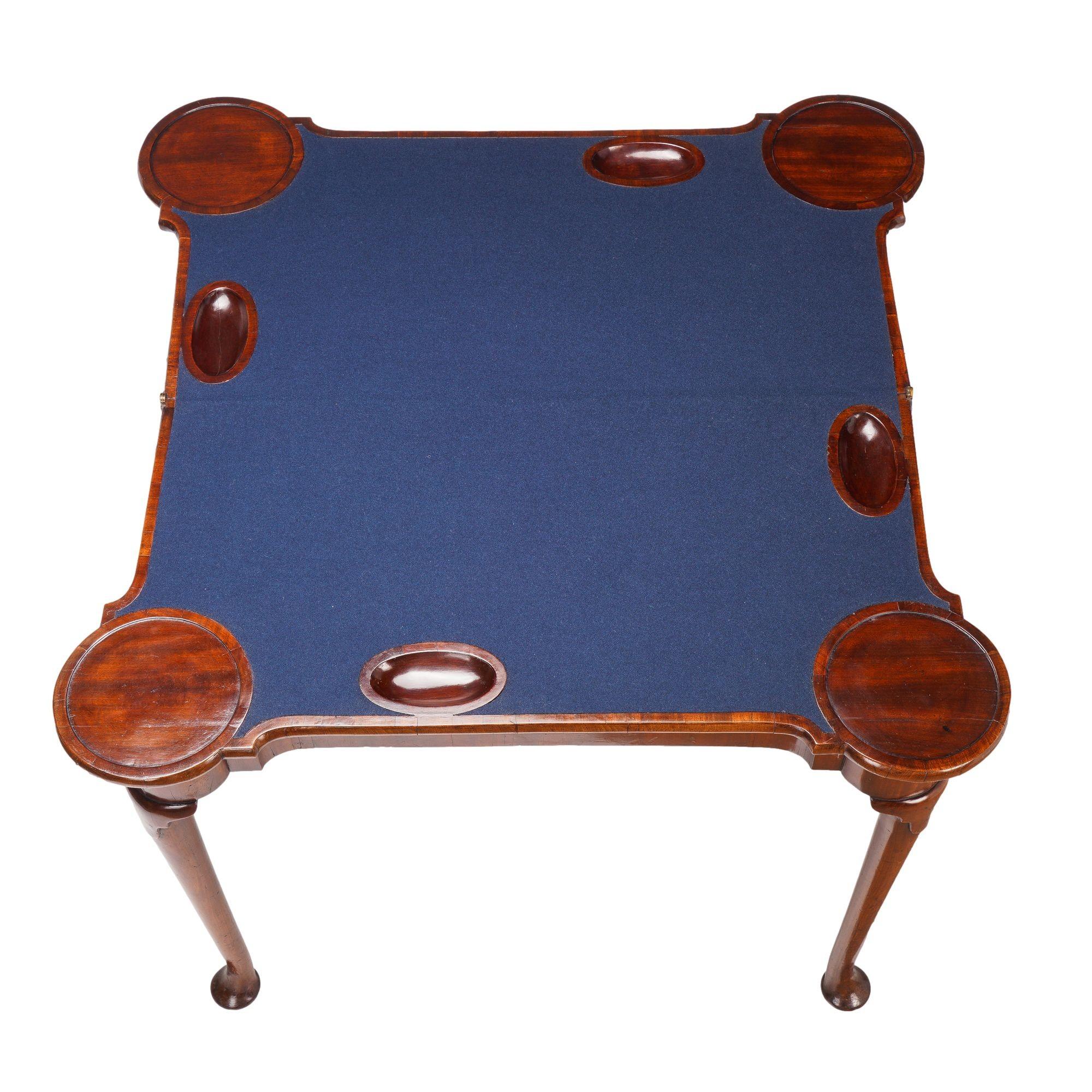 Queen Anne concertina action flip top game table. The table is designed with lieu pockets and turreted porringer corners constructed of mahogany and matched mahogany veneers on English oak. The gaming surface is covered with a replaced indigo blue