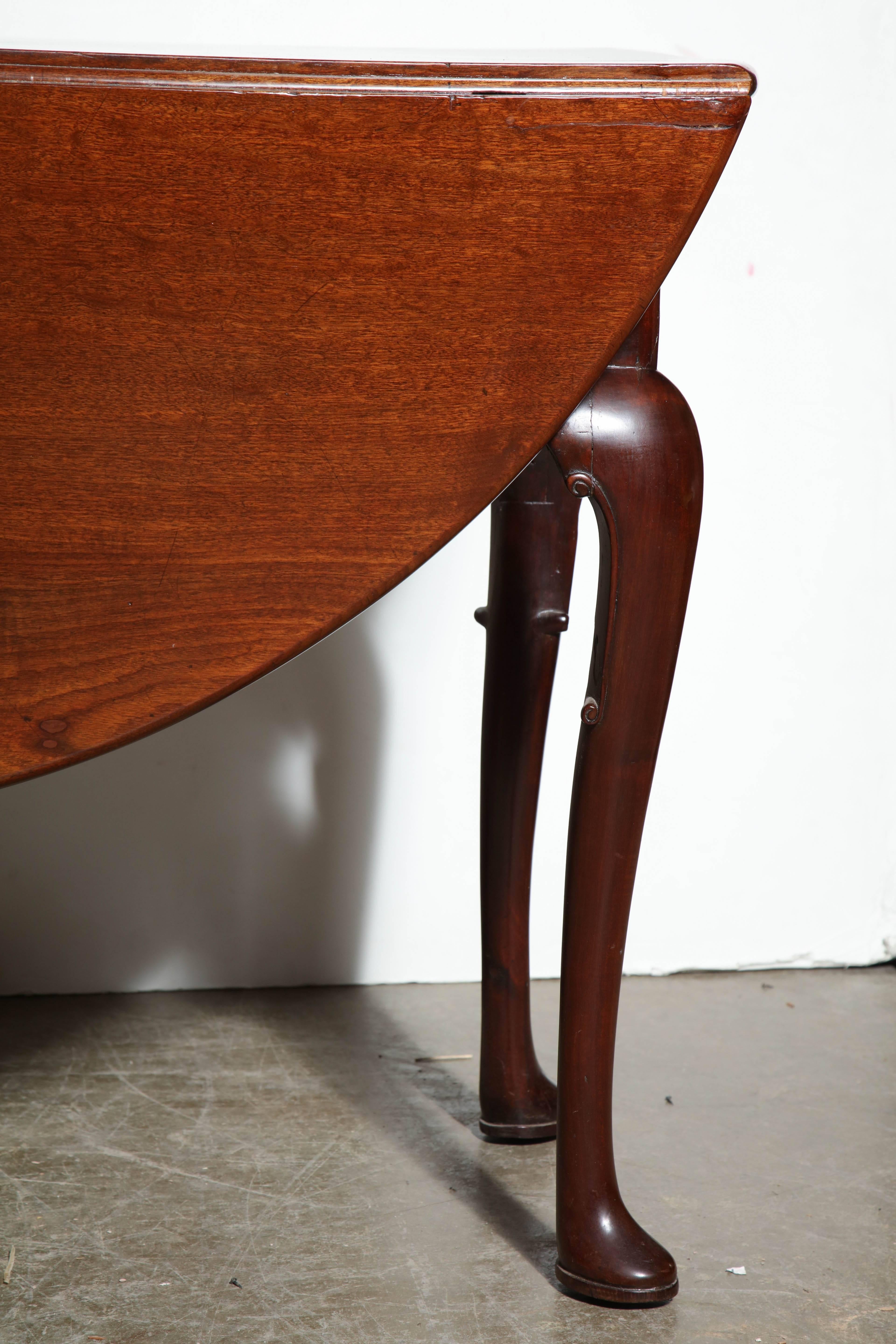 English Queen Anne mahogany rounded drop-leaf table with 'C' scroll knees and pad feet.
 