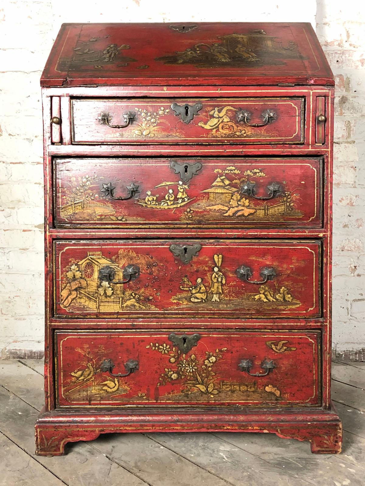 A small early 18th century red lacquer chinoiserie decorated commode with a desk compartment, the hinged slant front - flip top, supported by pull-out bars left and right, revealing four open compartments above three serpentine front drawers behind