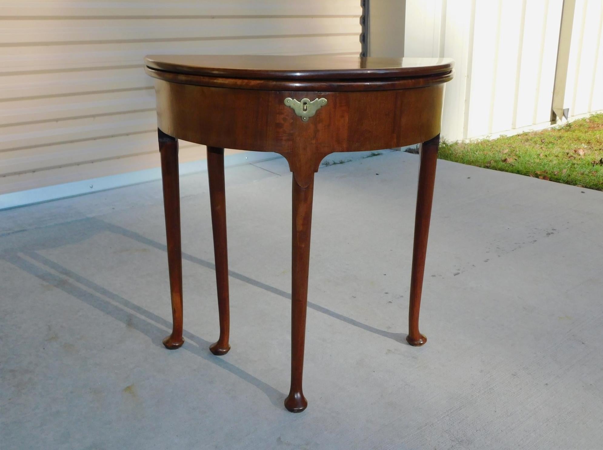 English Queen Anne one board mahogany game table with interior leather card playing surface, four oval poker chip holders, exterior brass bat wing escutcheon with locking mechanism, supporting rear gate leg, and resting on the original cabriole legs