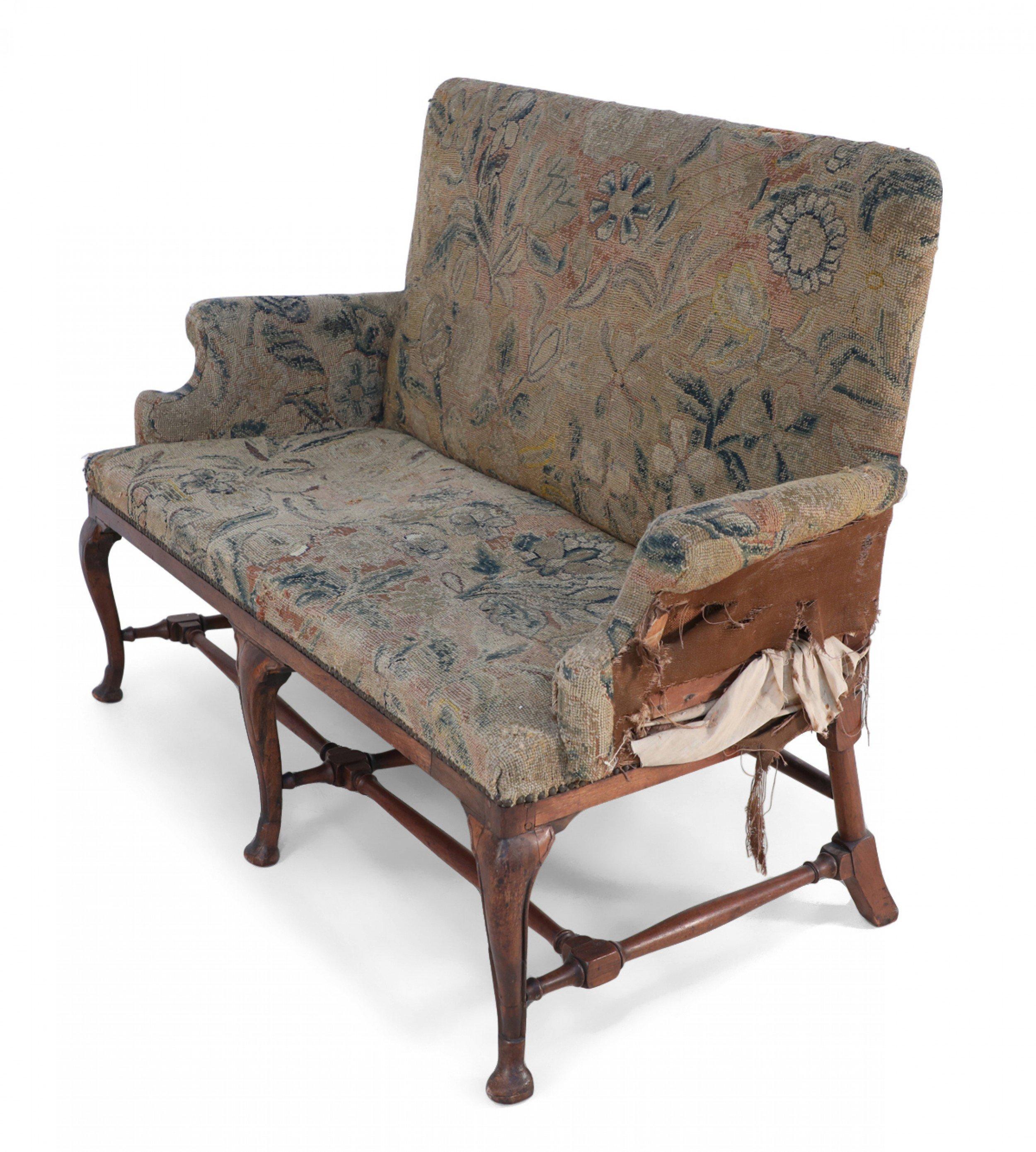 English Queen Anne (18th Century) loveseat with floral needlepoint tapestry upholstery (as is) and a walnut frame with a stretcher base and cabriole legs ending in pad feet.
 