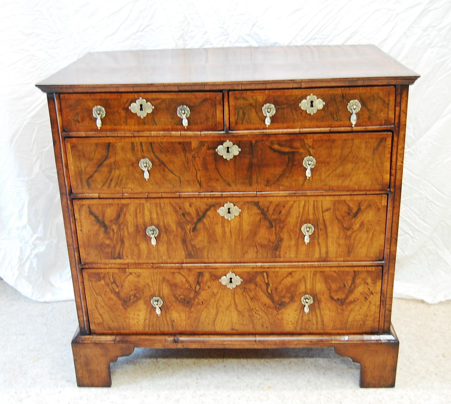   English Queen Anne period figured walnut chest of five graduated drawers.  The initial photo represents the true color of this chest -a rich honey color; most of the detail photos are a little darker than the chest actually is, apologies. The