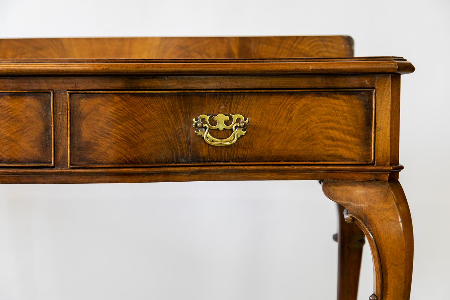 English Queen Anne Walnut Serving Table has a serpentine front and chamfered corners. The top has elaborately figured walnut book matched veneer. The drawer fronts have flame grain walnut and the original brass open work handles. The legs are