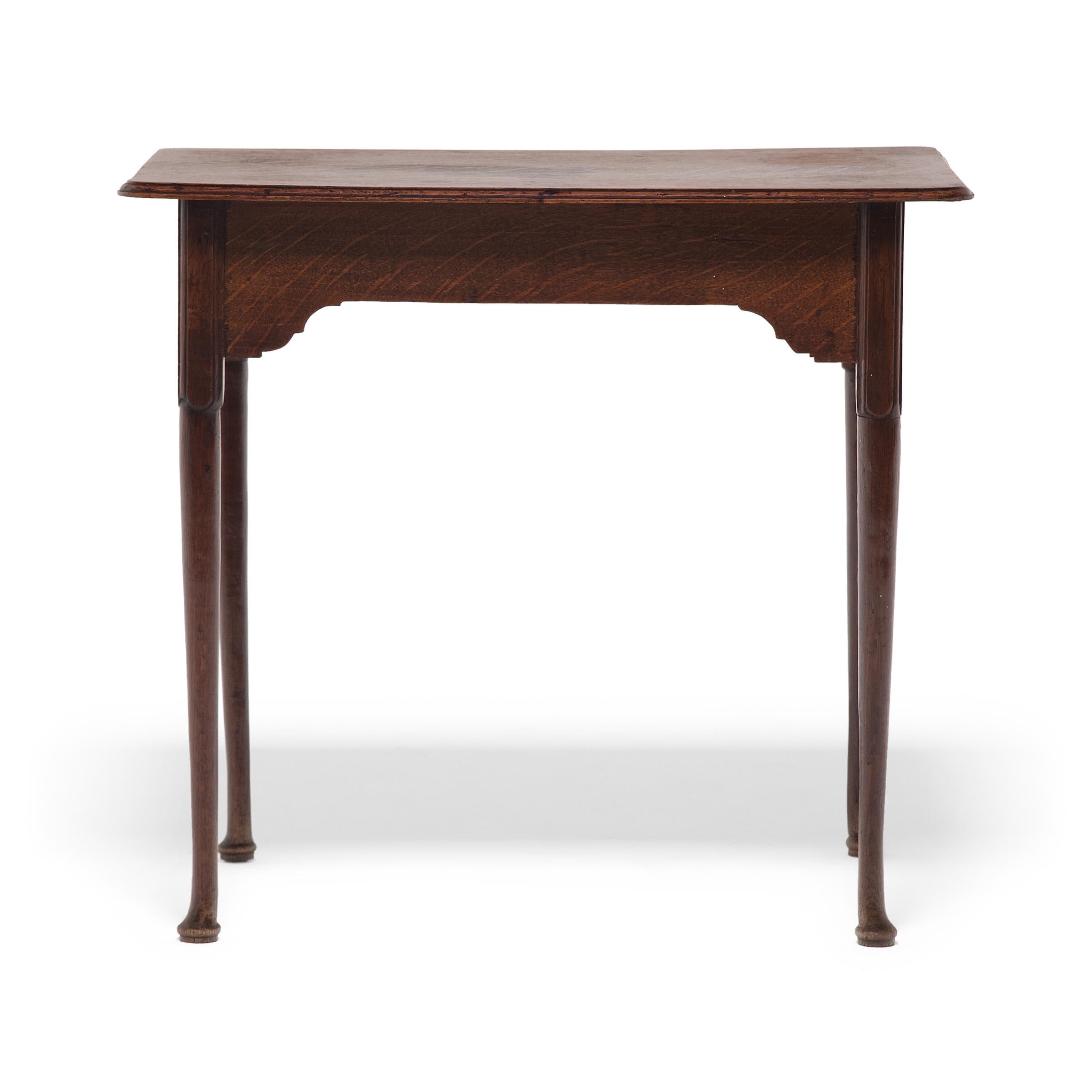 This antique English side table was crafted in the mid-19th century in the style of Queen Anne furniture. Although fairly basic, the table is beautifully crafted with a lightweight design and subtle carved detail to the legs and apron. The