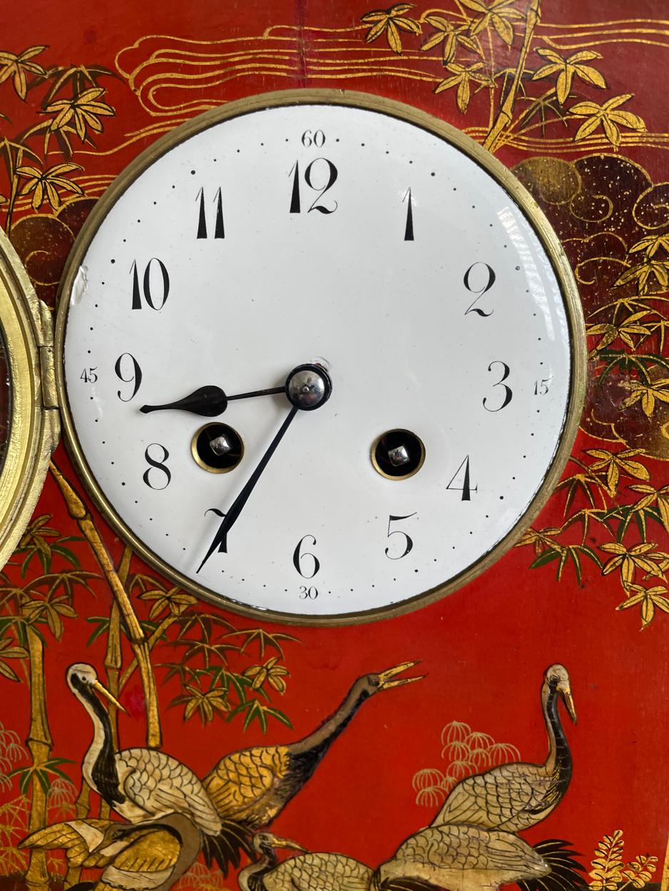 Pendule de manteau du début du 20e siècle, en bronze rouge et doré, décorée de grues parmi un motif floral, le cadran émaillé de 4 pouces avec des chiffres arabes et le boîtier avec un fleuron arrondi et deux poignées de transport, le mouvement