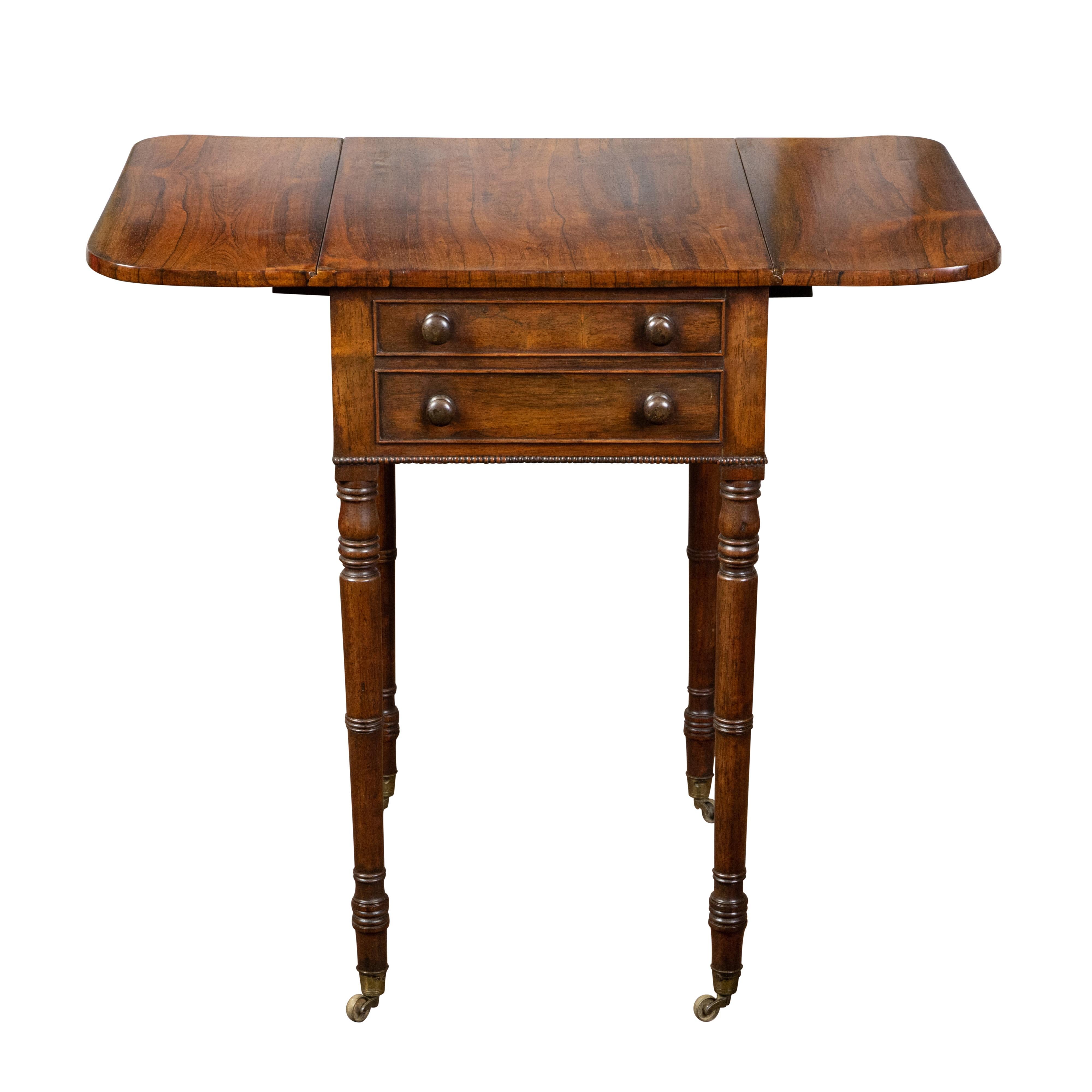 An English Regency period mahogany Pembroke table from the early 19th century, with two drop leaves and drawers. Created in England during the first quarter of the 19th century, this Pembroke table features a rectangular veneered top flanked with