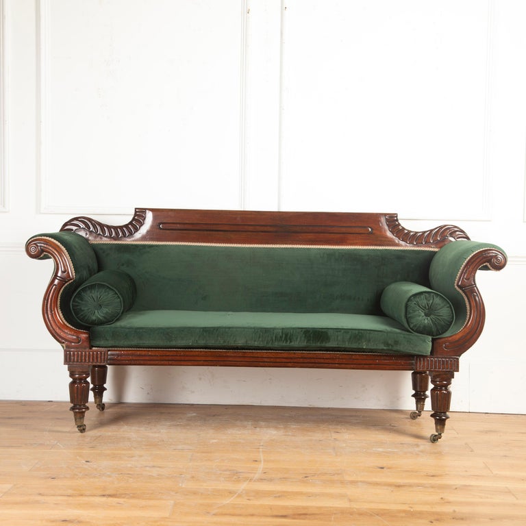 English early 19th century Regency mahogany sofa.

This gorgeous country house sofa features a deeply carved mahogany frame with a deep aged patina.

The flat-arched top rail is flanked on either side by bold gadrooning behind the beautifully
