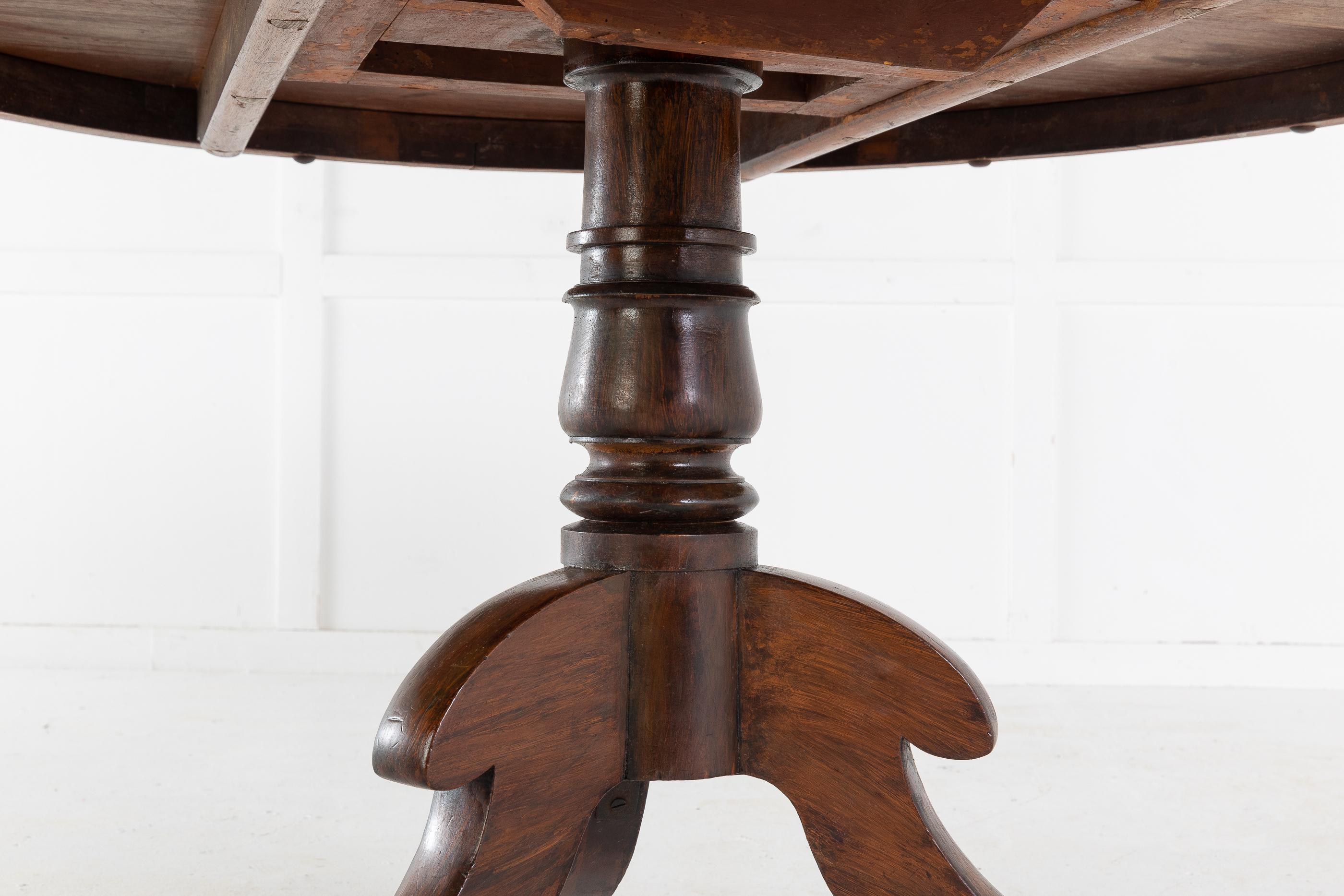 English Regency 19th century rosewood circular centre table. The top having a border of crossbanding, above the shallow inset frieze. Supported on a turned, simulated rosewood, pedestal base terminating in three outswept legs with brass castors.