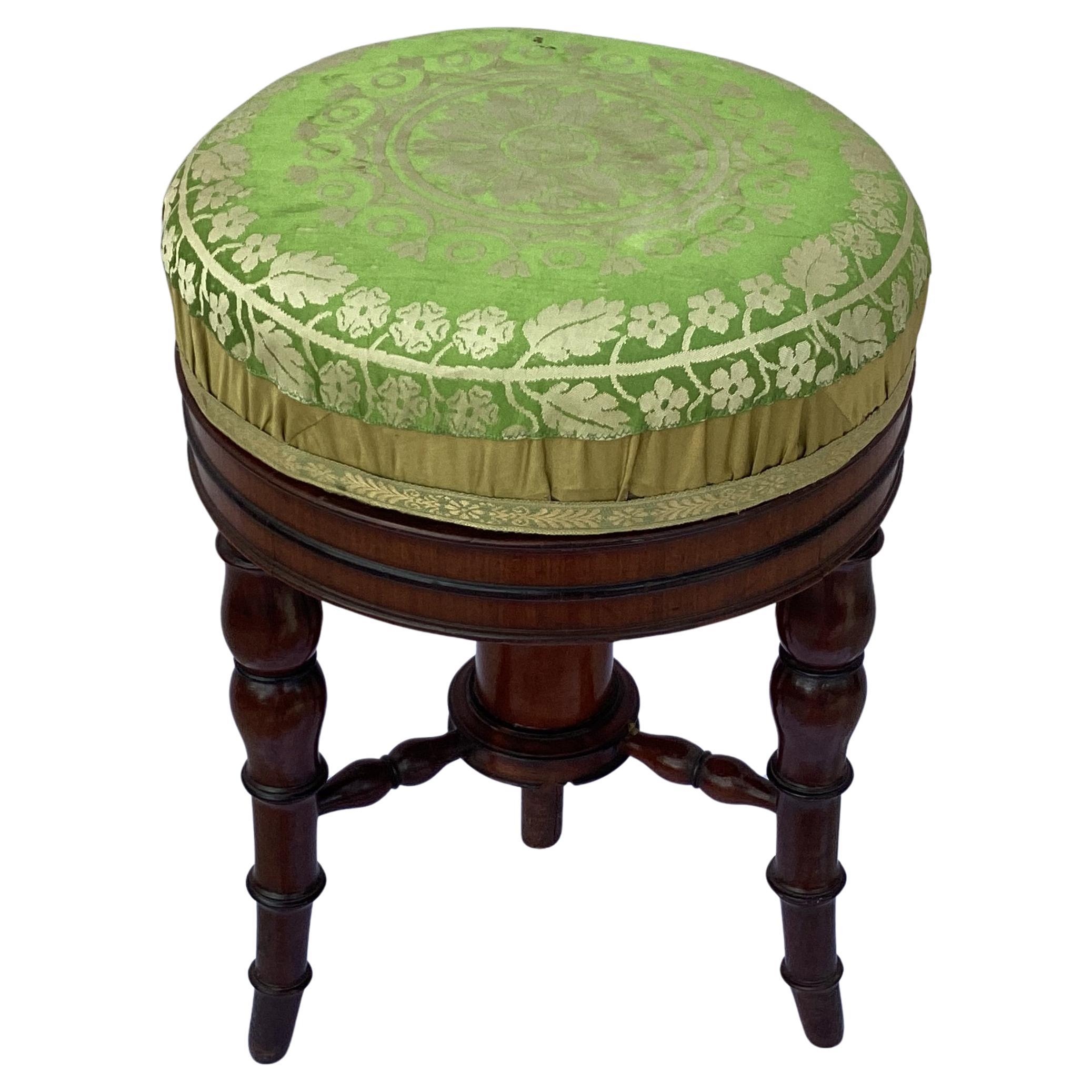 19th Century English Regency Mahogany Piano Stool with Round Upholstered Seat. Rotating seat features beautiful green padded upholstery that adds vibrancy and opulence to the room, aligning with the period's use of rich, luxurious fabrics. Seat is