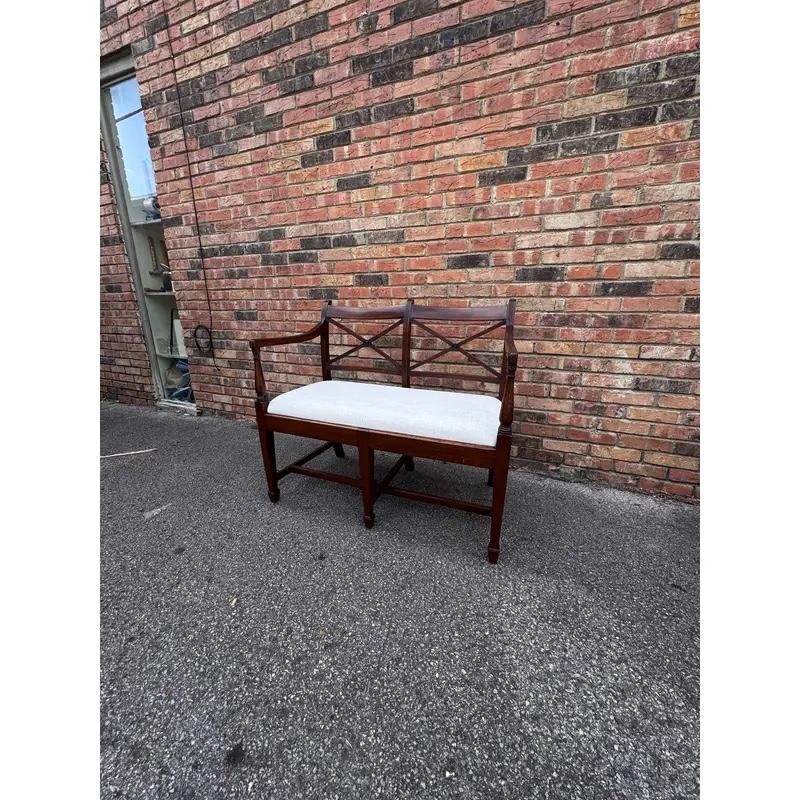 Coming to you from early 19th-century England, this Regency-era piece is both stylish and sturdy. The solid wood with crossed back can easily support two people sitting with an armrest on each side. The comfortable seat has been recently